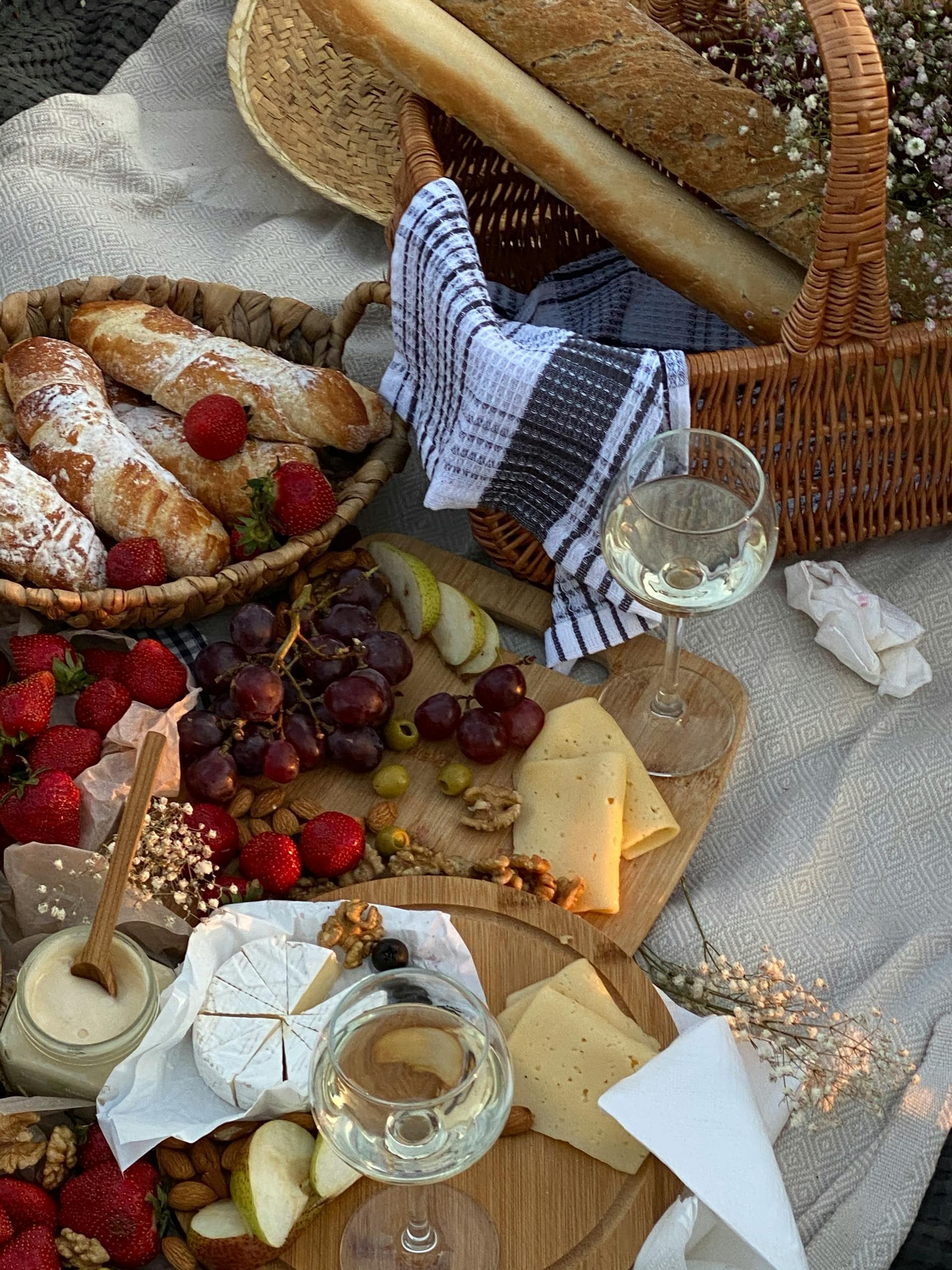 Tablas de madera con quesos y frutos al lado de las canastas con pan.
