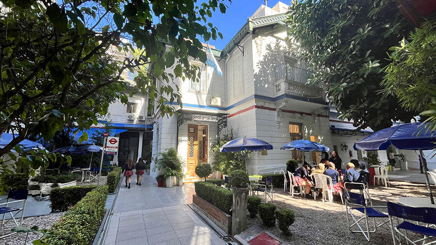 Casa blanca con sombrillas azules delante de la entrada.