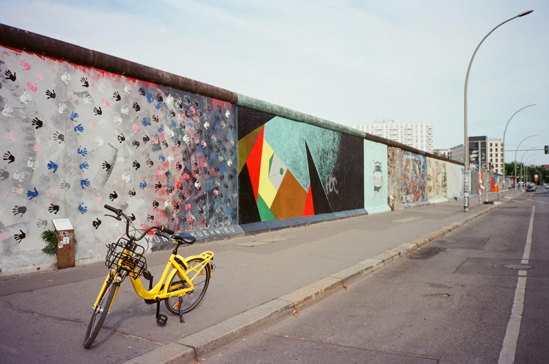 Mural de colores detrás de la bicicleta amarilla.