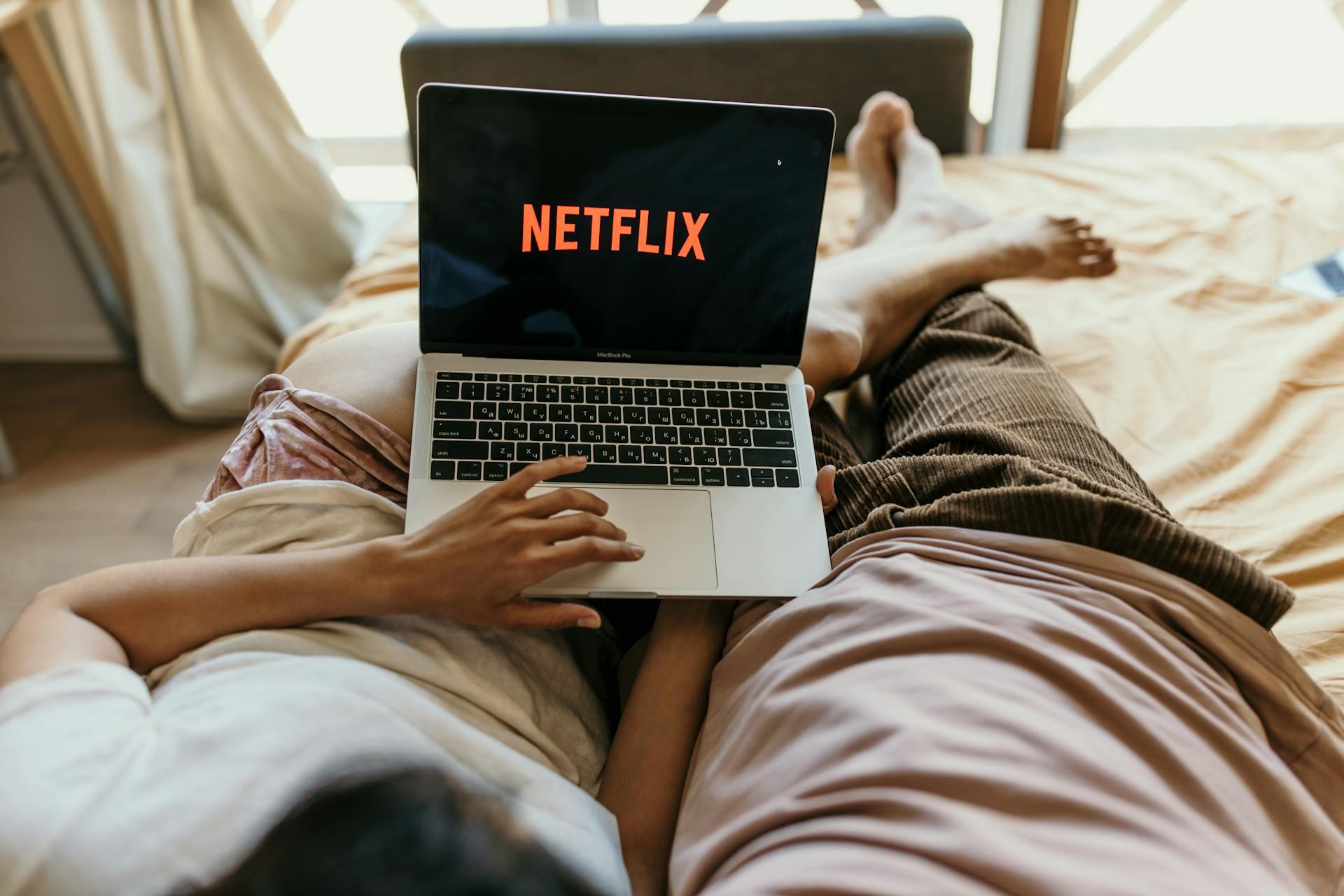 Dos personas acostadas sosteniendo una PC con Netflix.