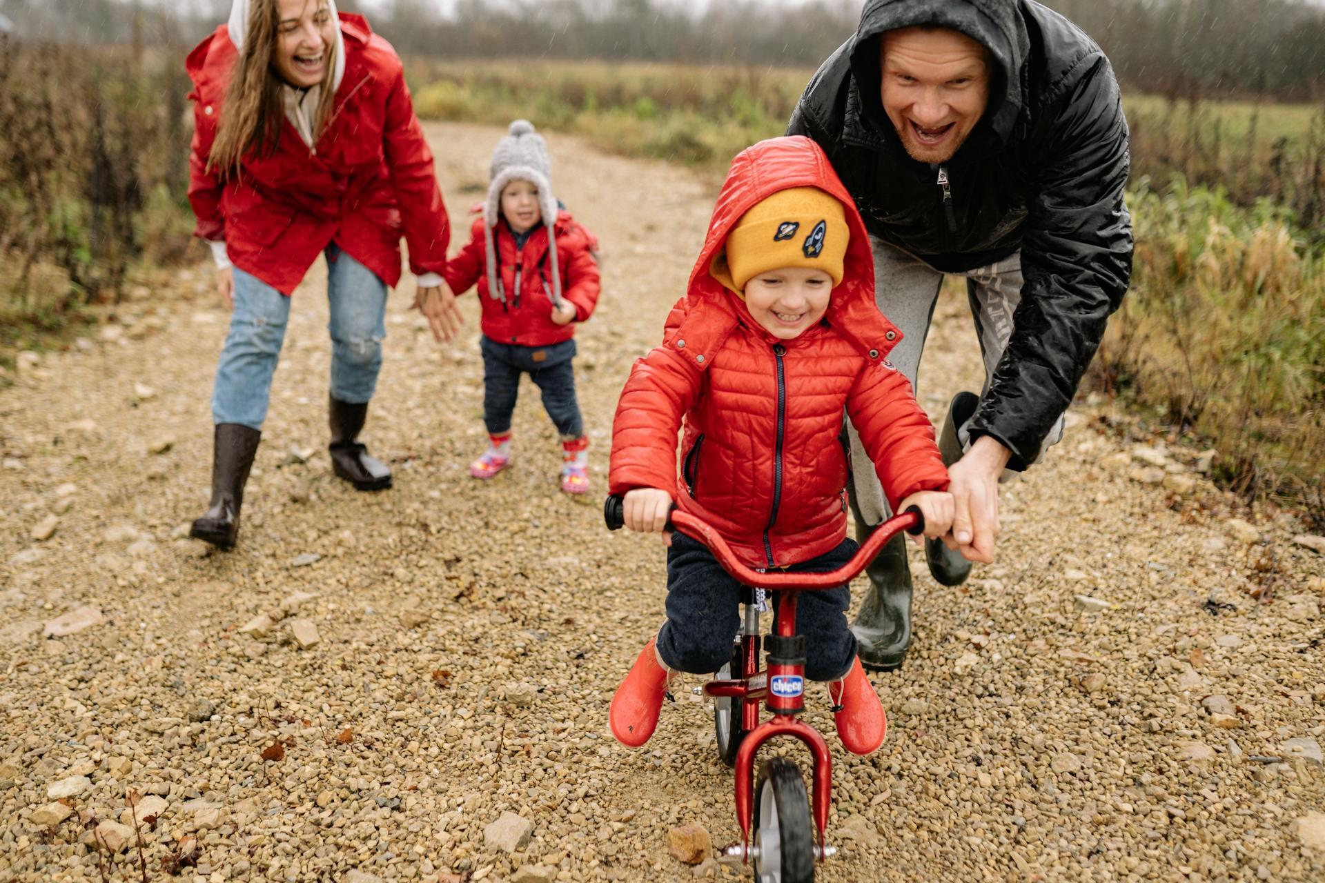 Niños y padres jugando con la bicicleta al aire libre.