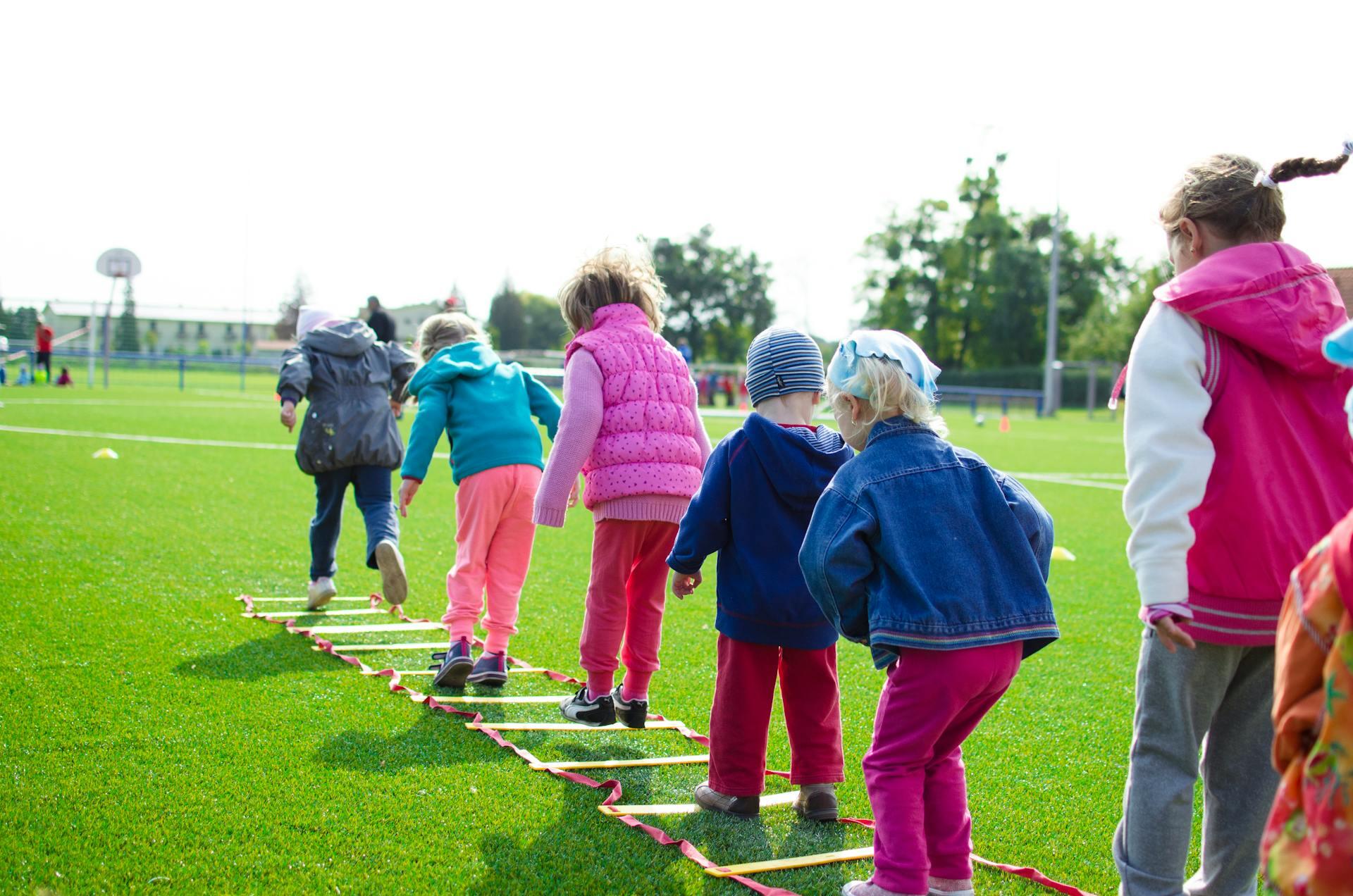 Niños jugando en fila sobre el césped.