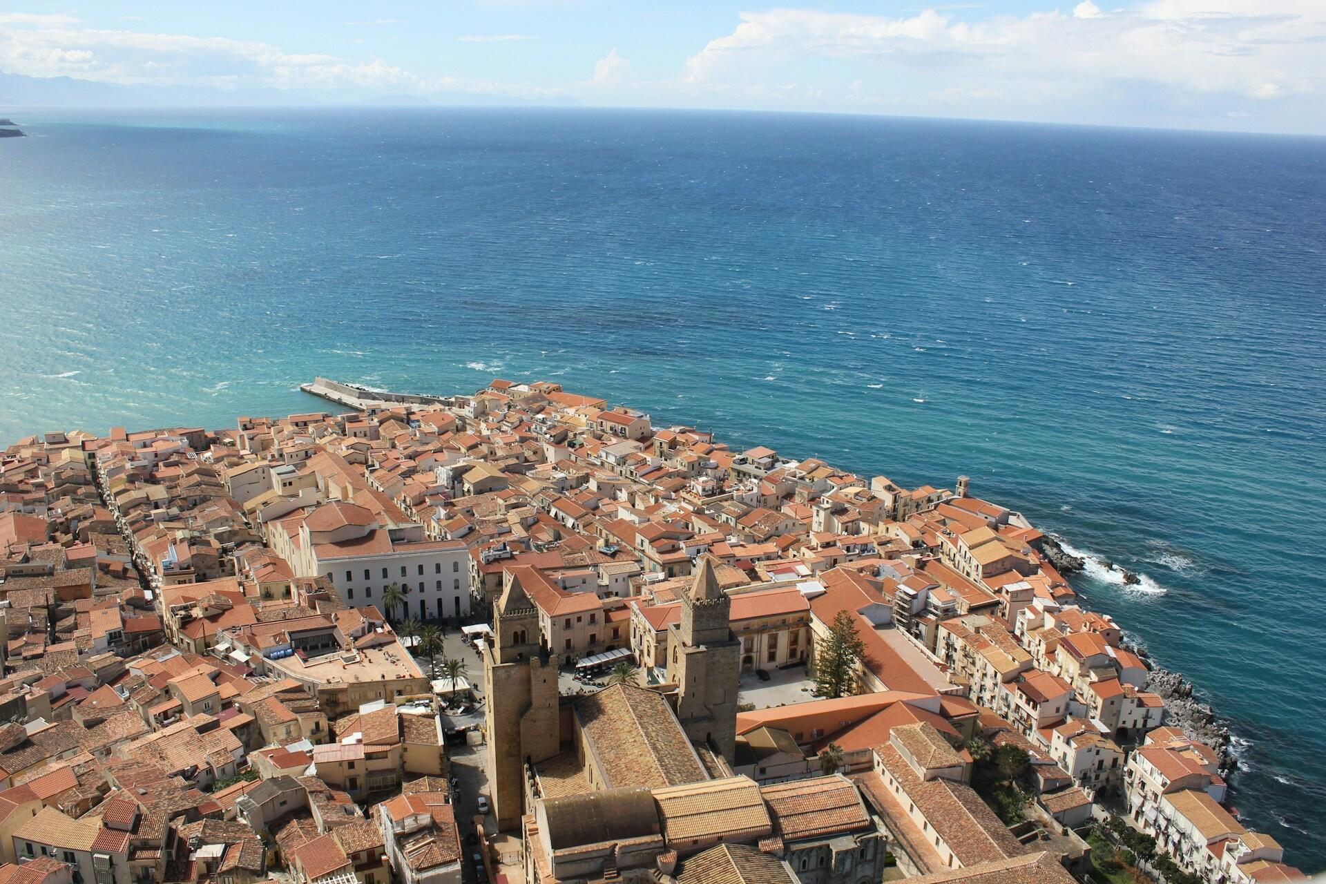 Vista aérea de una ciudad con casas de techos marrones al lado del mar. Fuente: Catherine Grace Cumming