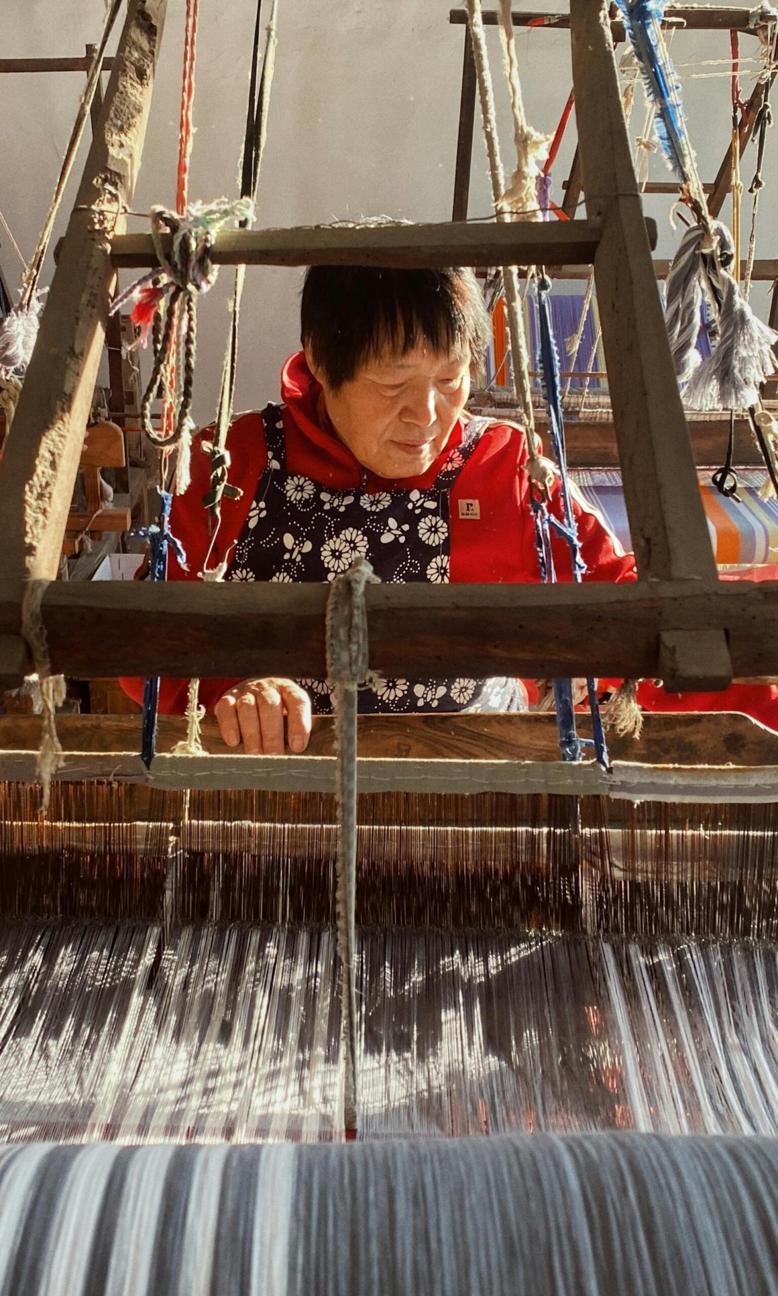 Mujer mayor tejiendo en un telar tradicional, representando las costumbres y la herencia cultural indígena, por jiaze wang.