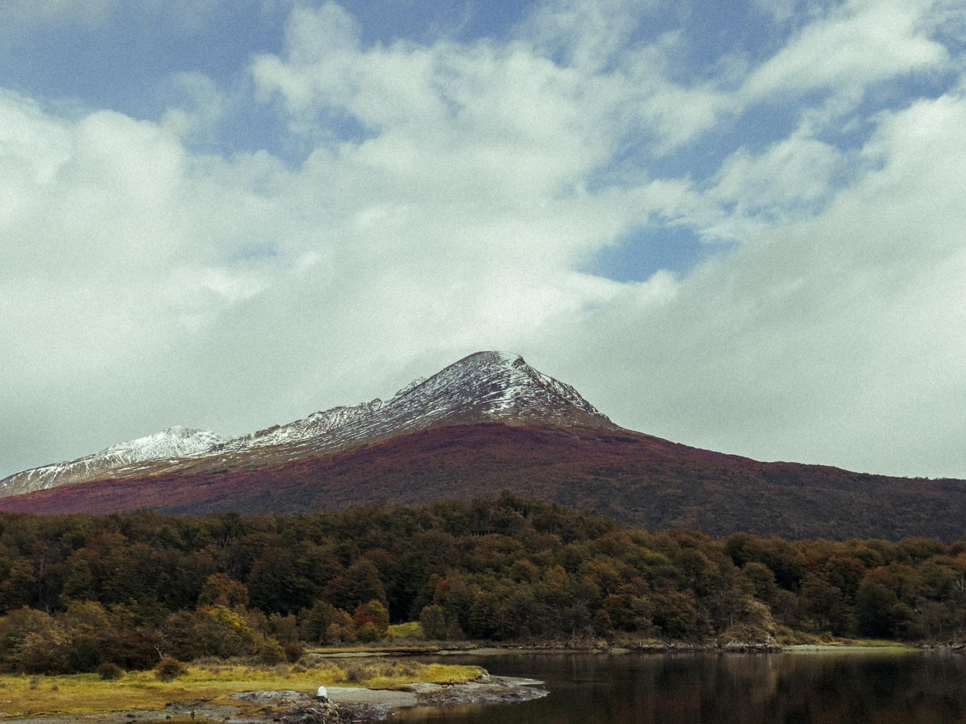 Paisaje montañoso y bosque otoñal a orillas del agua en Ushuaia, Tierra del Fuego, fotografiado por Caroline Cagnin en Pexels.