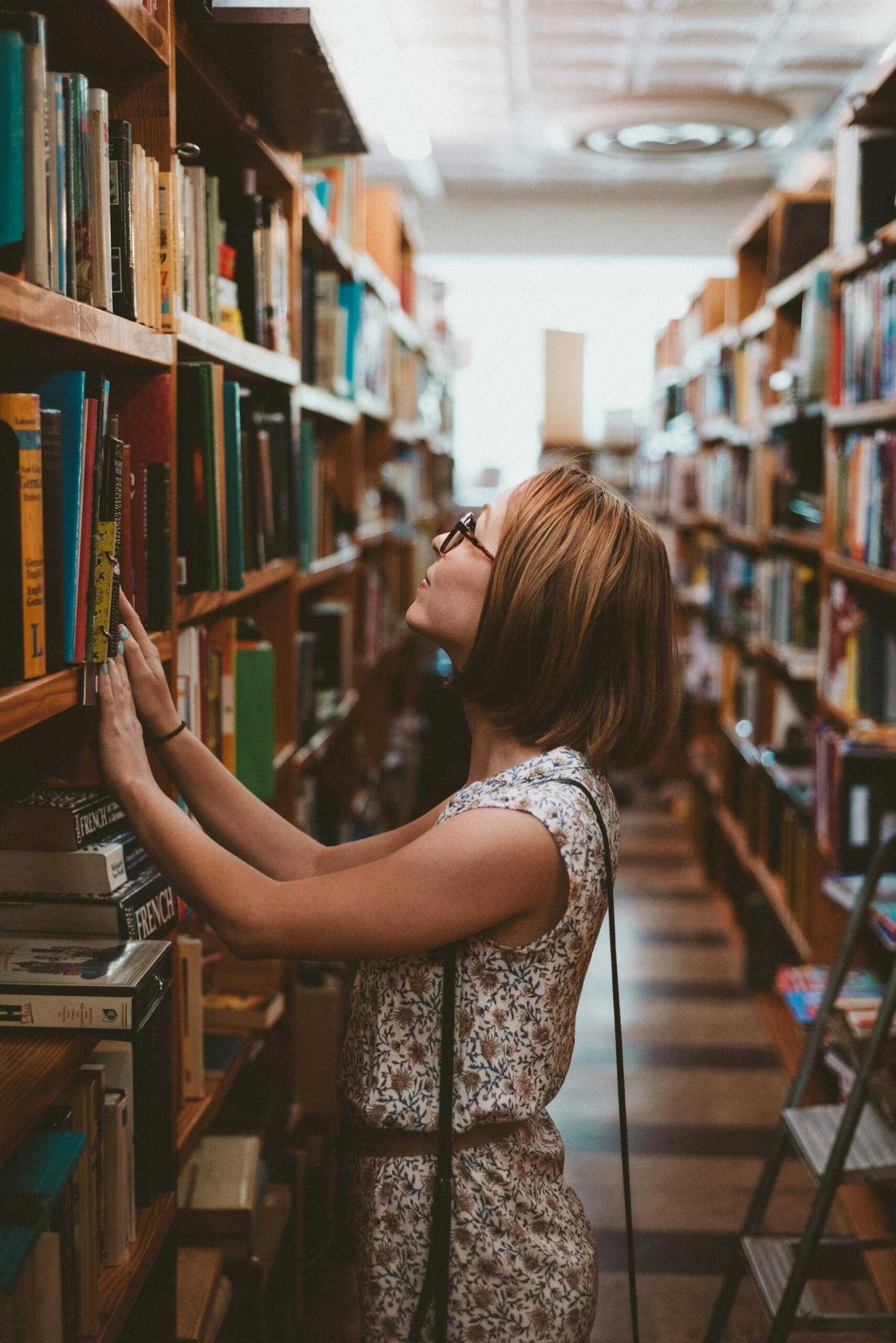 Mujer parada delante del estante con libros de la biblioteca.