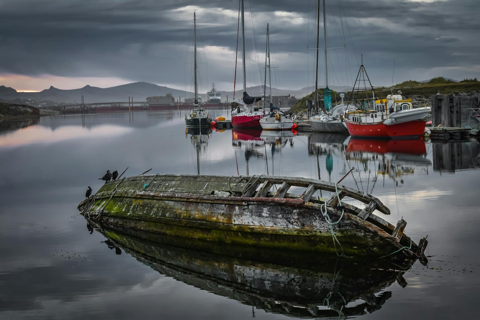 Barco abandonado en el puerto de Stanley, Islas Malvinas, con veleros de fondo. Foto: Klajdi Cena.
