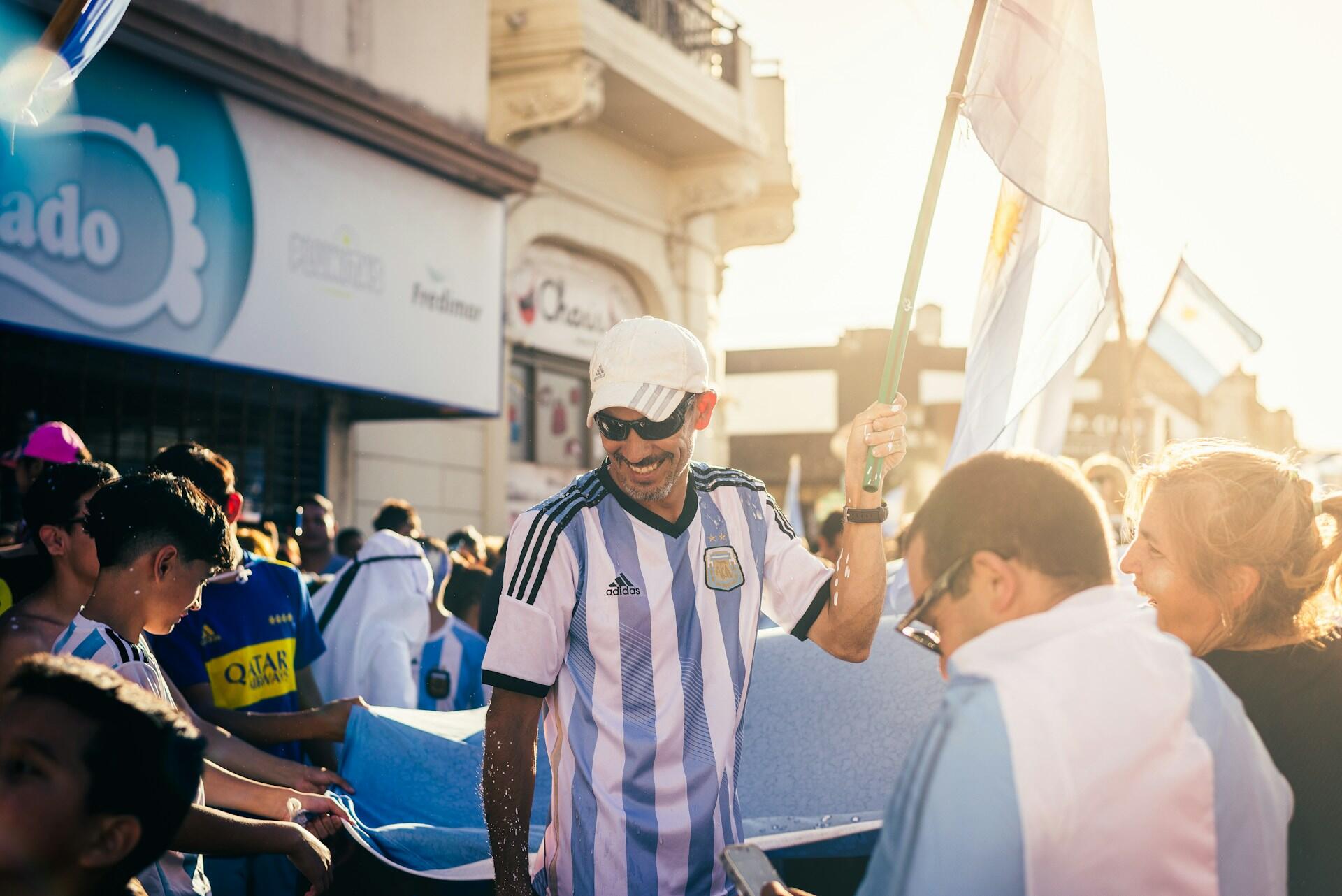 Argentina. Un hincha argentino sonriendo con la camiseta de la selección y una bandera durante los festejos. Fotografía de Agustin Fernandez.