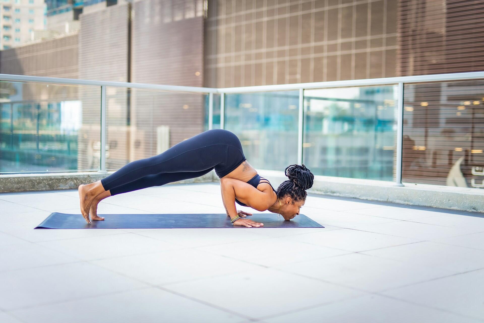 Mujer acostada boca abajo sobre el mat sosteniendo su cuerpo con las manos.