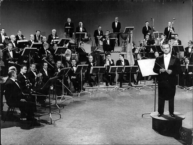 Imagen en blanco y negro de una orquesta y su director.