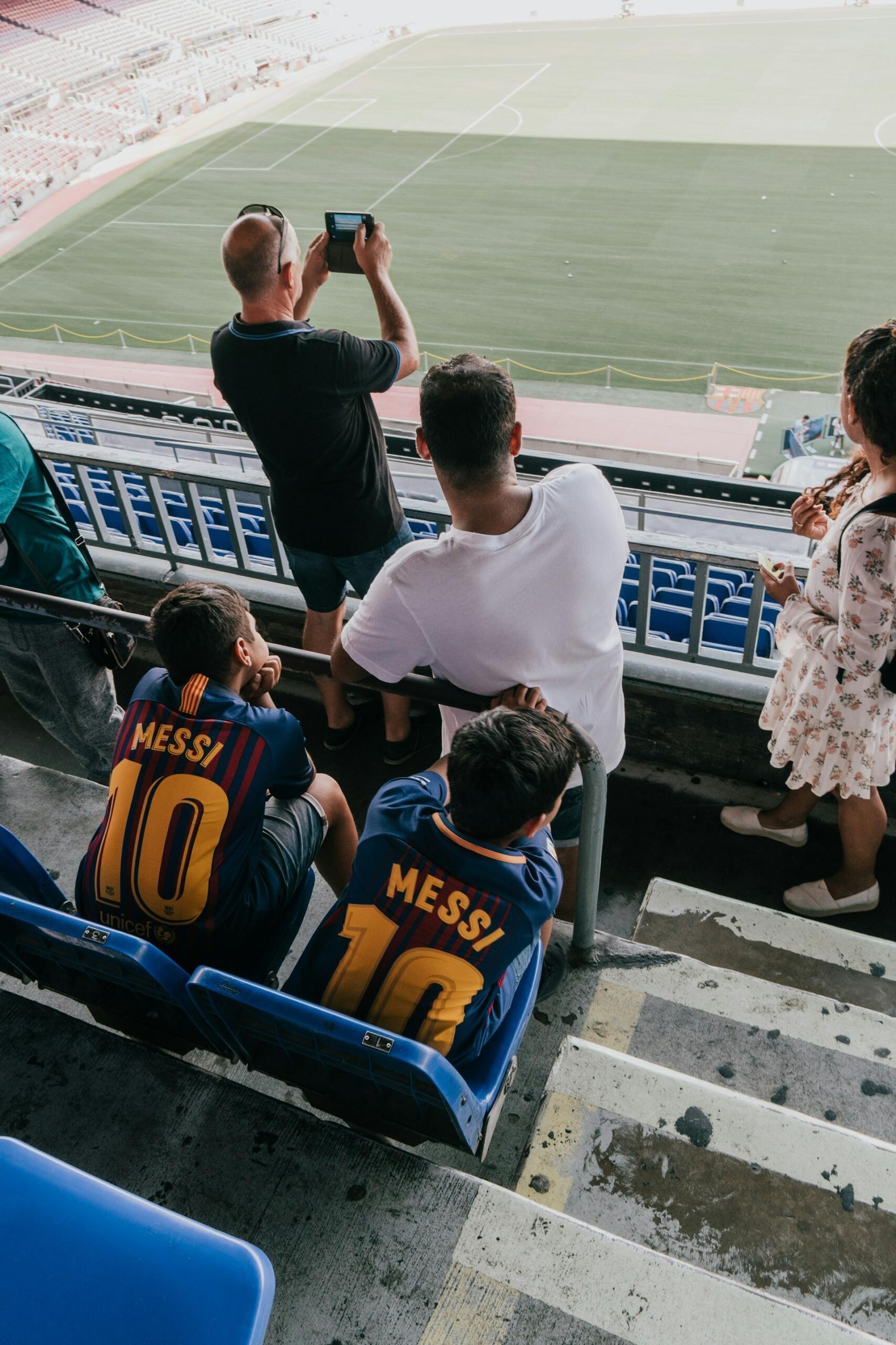 En el Camp Nou de Barcelona, dos niños con camisetas de Messi del FC Barcelona miran el campo desde las gradas. Foto de Dmitry Tomashek.