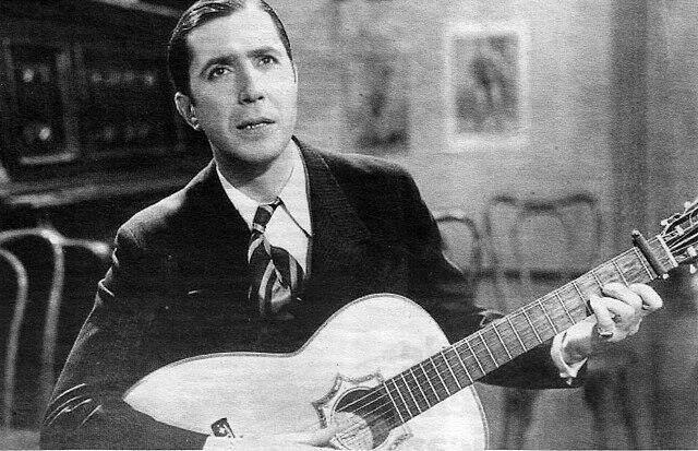 Fotografía en blanco y negro de un hombre sosteniendo una guitarra.