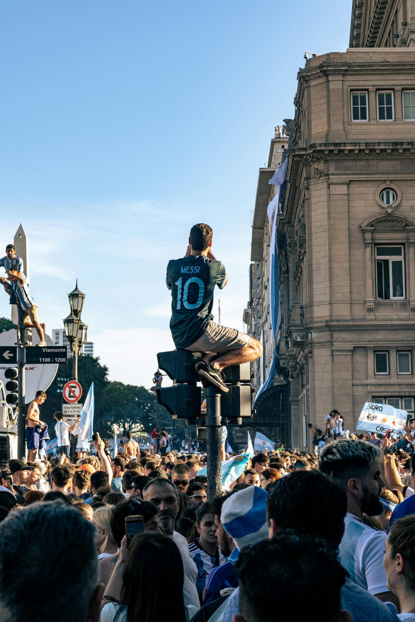 En Buenos Aires, Argentina, un hincha con la camiseta 10 de Messi celebra subido a un semáforo durante los festejos masivos. Foto de Fabrízio Vélez.