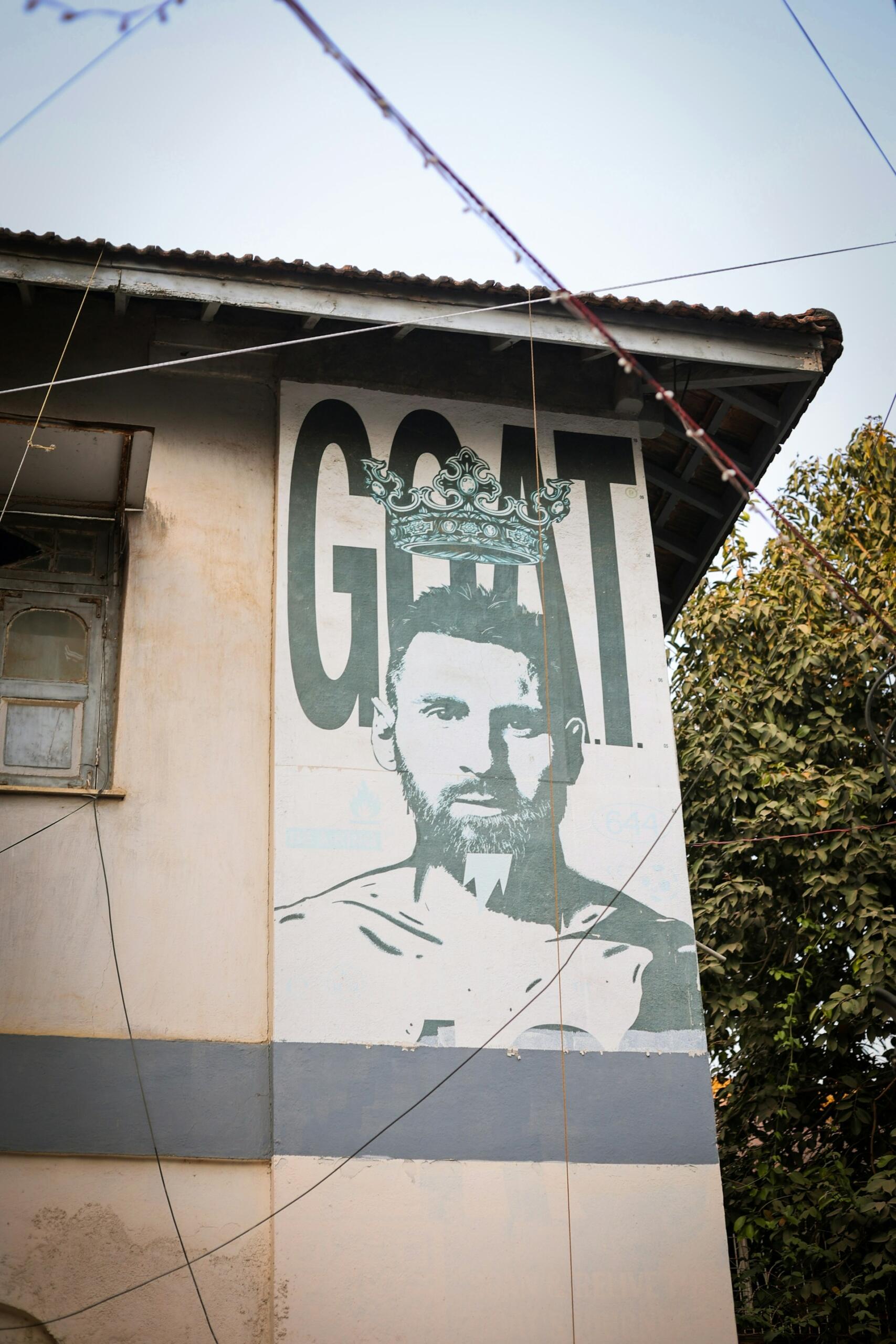 Mural gigante en la pared de un edificio con el rostro de Lionel Messi coronado y la palabra
