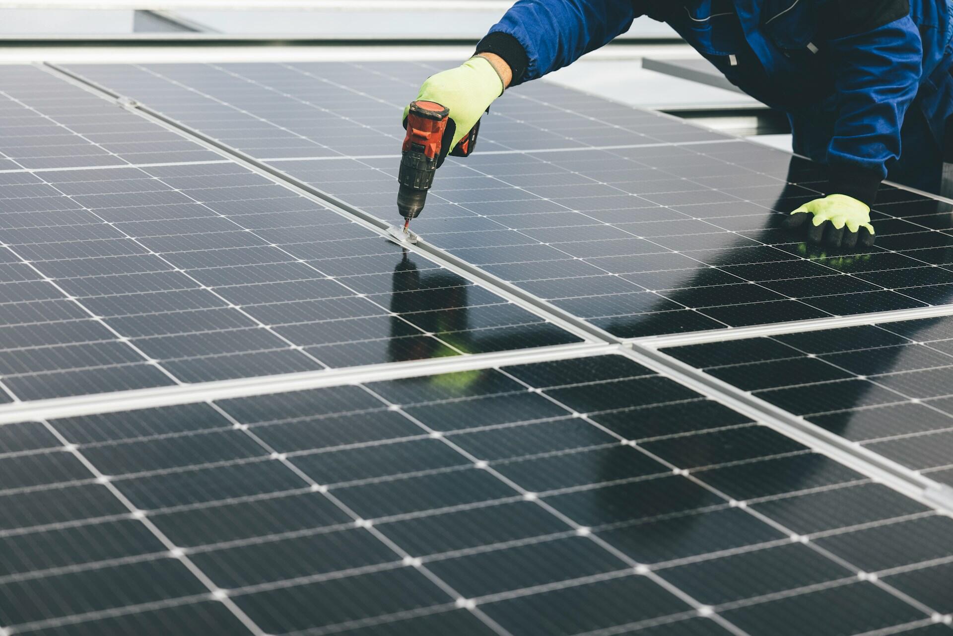 Un trabajador instalando paneles solares en un techo, tecnología fundamental para generar hidrógeno verde en el norte argentino. Fotografía de Markus Spiske.