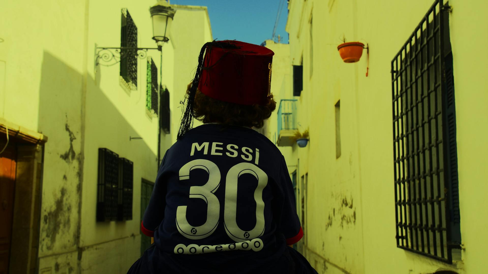 Tunis, Túnez: un niño de espaldas camina por una calle con la camiseta 30 de Messi del PSG y un fez tradicional. Foto por Riadh Sahli.