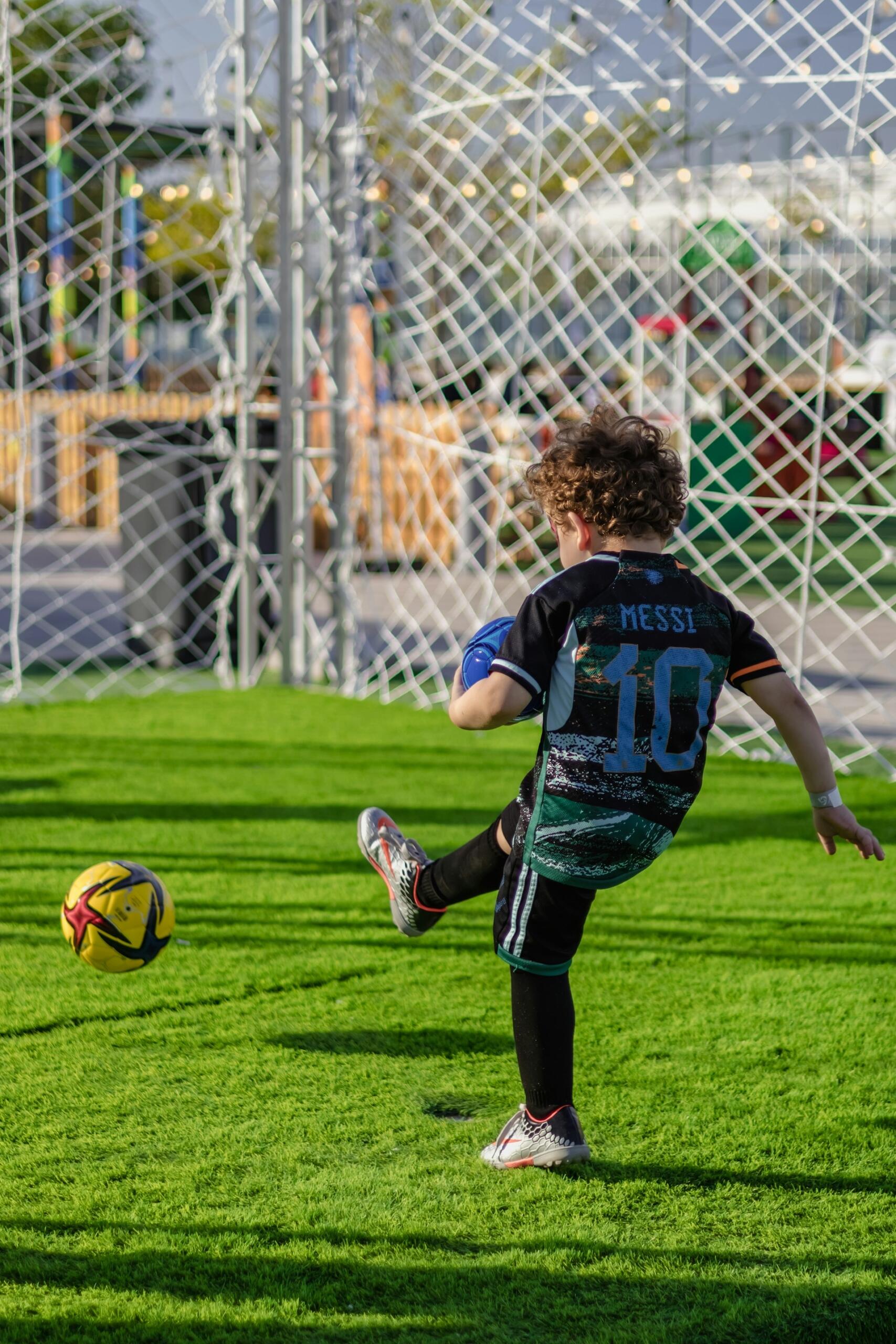 Un niño patea una pelota de fútbol vistiendo una camiseta con el nombre MESSI y el número 10. Fotografía por ANOOF C.