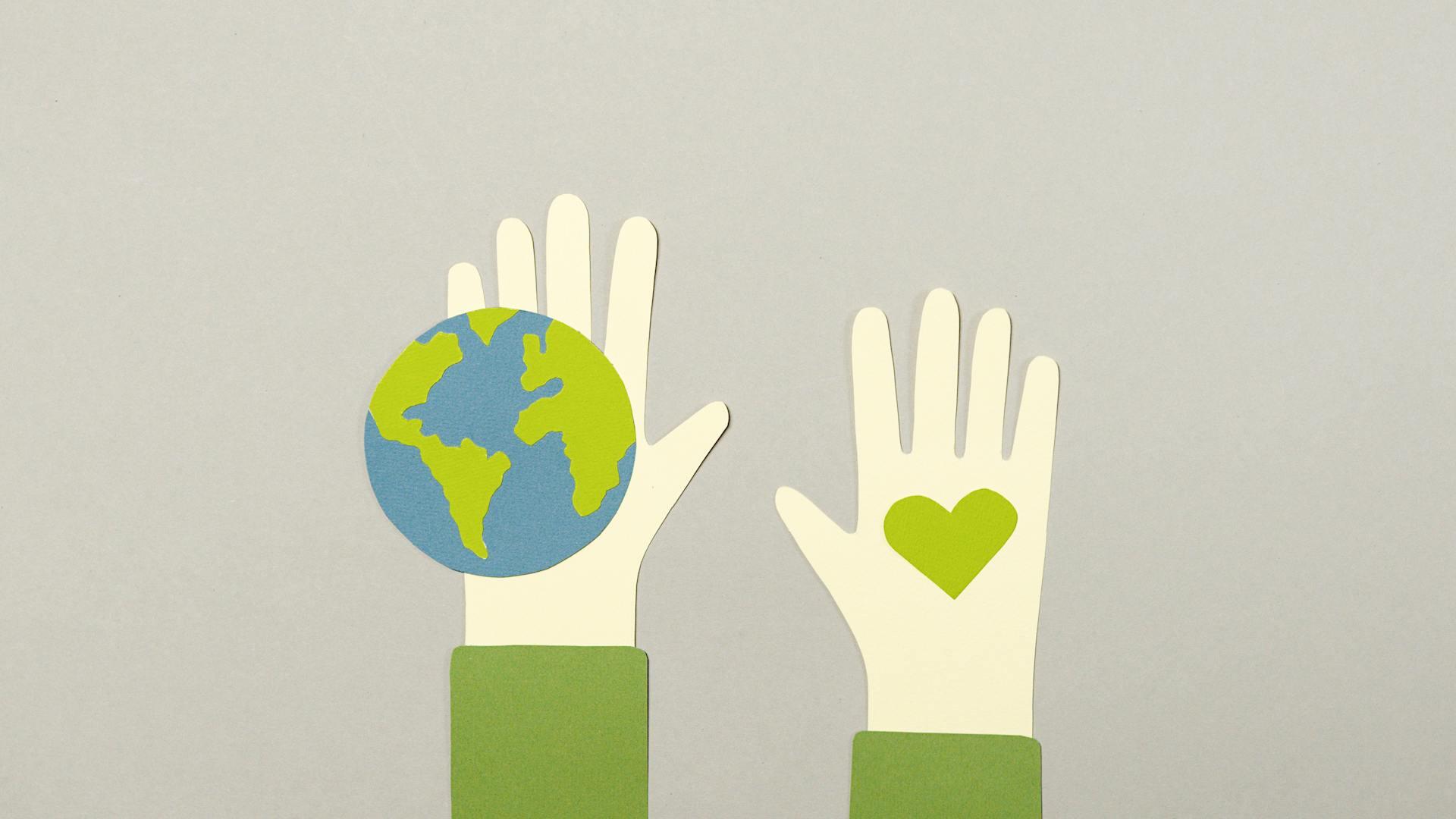 Ilustración de papel con manos sosteniendo el planeta Tierra y un corazón verde, representando la sostenibilidad y la descarbonización. Fotografía de Artem Podrez.