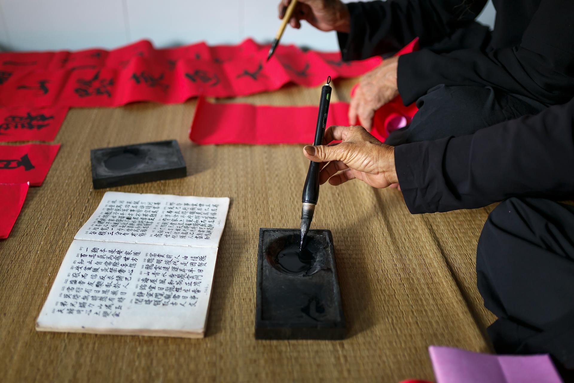 ersona recargando tinta en pincel durante práctica de escritura china, fotografía de Quang Nguyen Vinh para Pexels 
