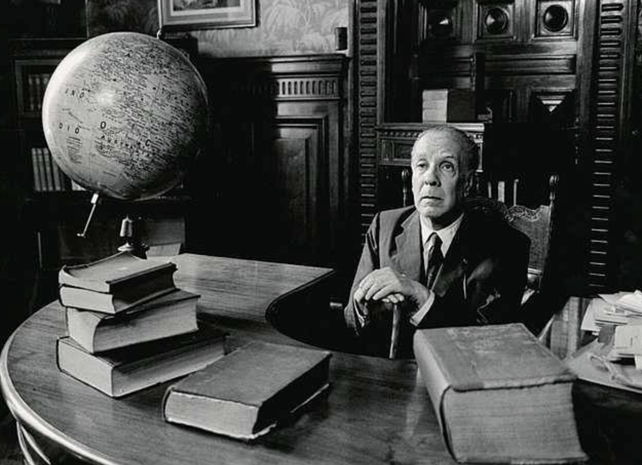 orge Luis Borges sentado en su escritorio rodeado de libros y un globo terráqueo, en la Biblioteca Nacional de Buenos Aires. Fuente: Google Common License.