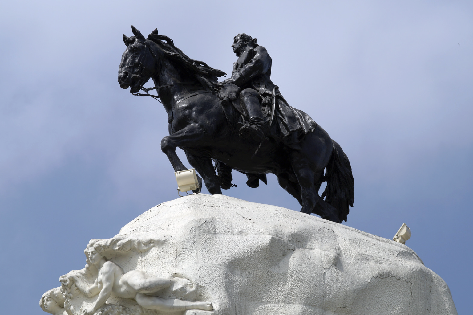Primer plano del monumento ecuestre de San Martín sobre un pedestal de piedra, vista desde un ángulo contrapicado.