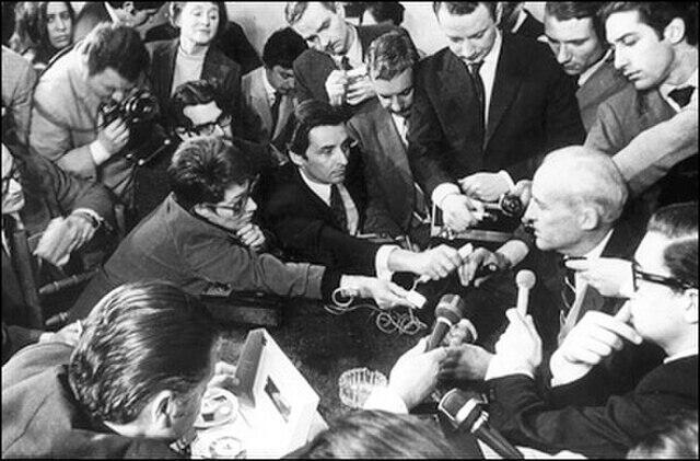 Periodistas con micrófono al rededor de un hombre.