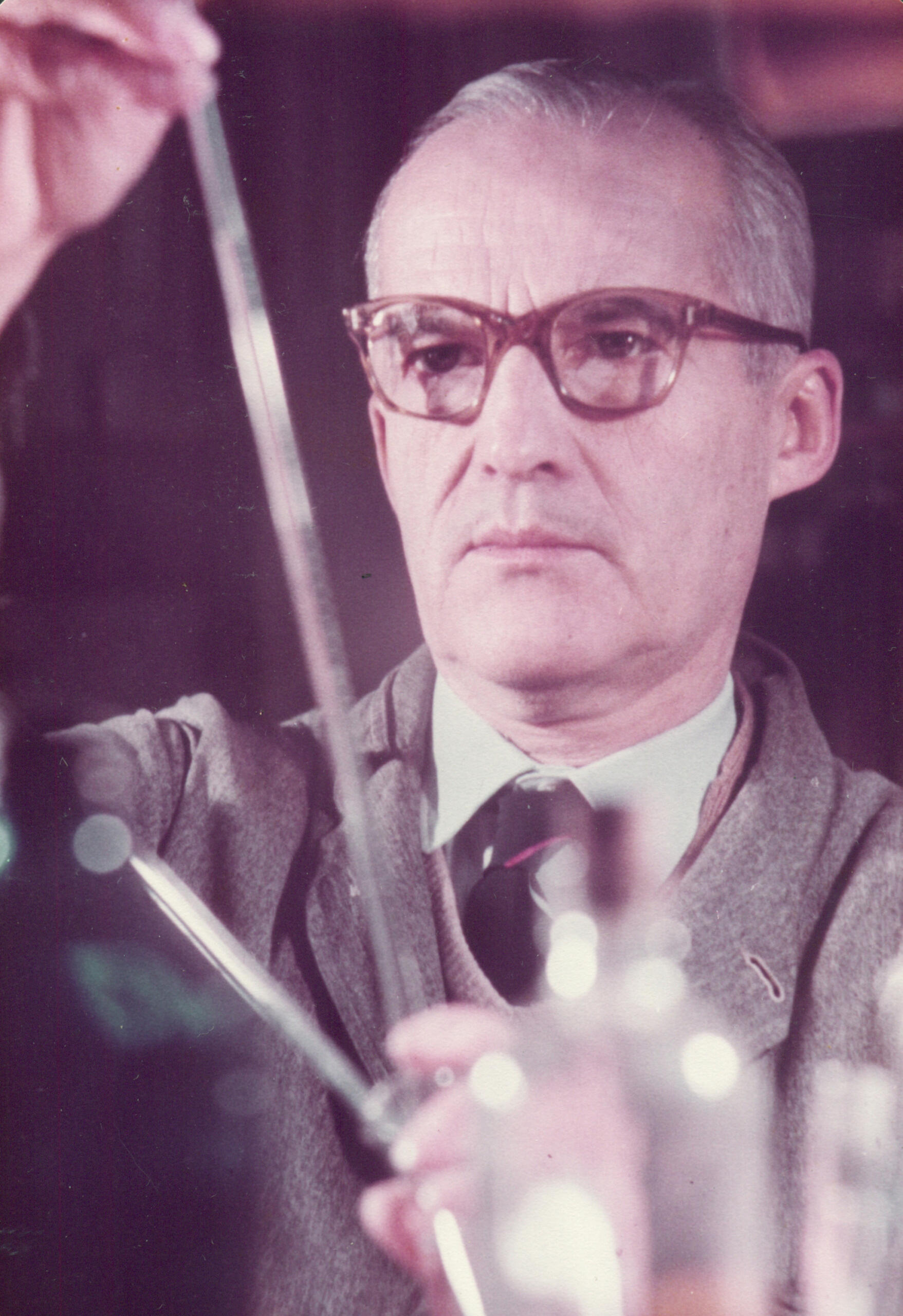 Hombre con anteojos sosteniendo una varilla.