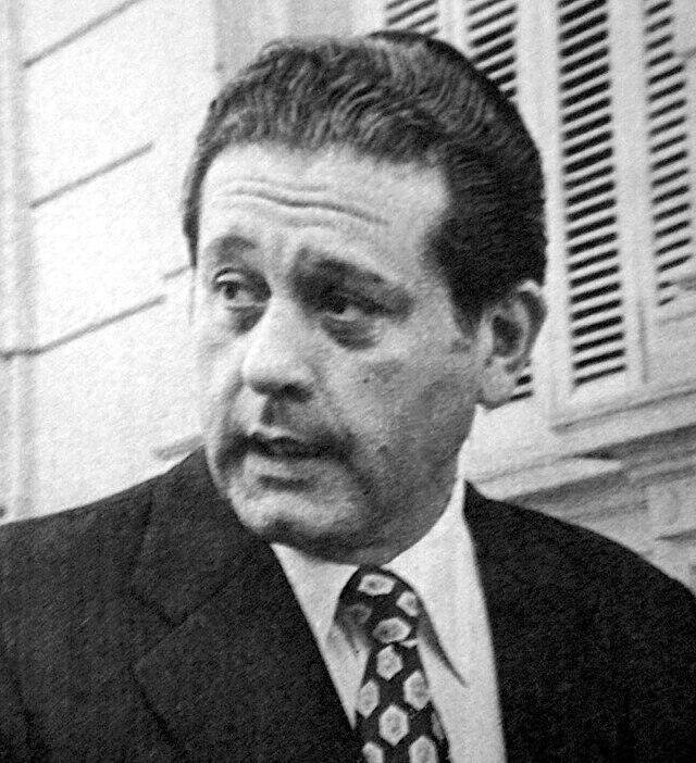 Imagen blanco y negro de un hombre con camisa, saco y corbata.