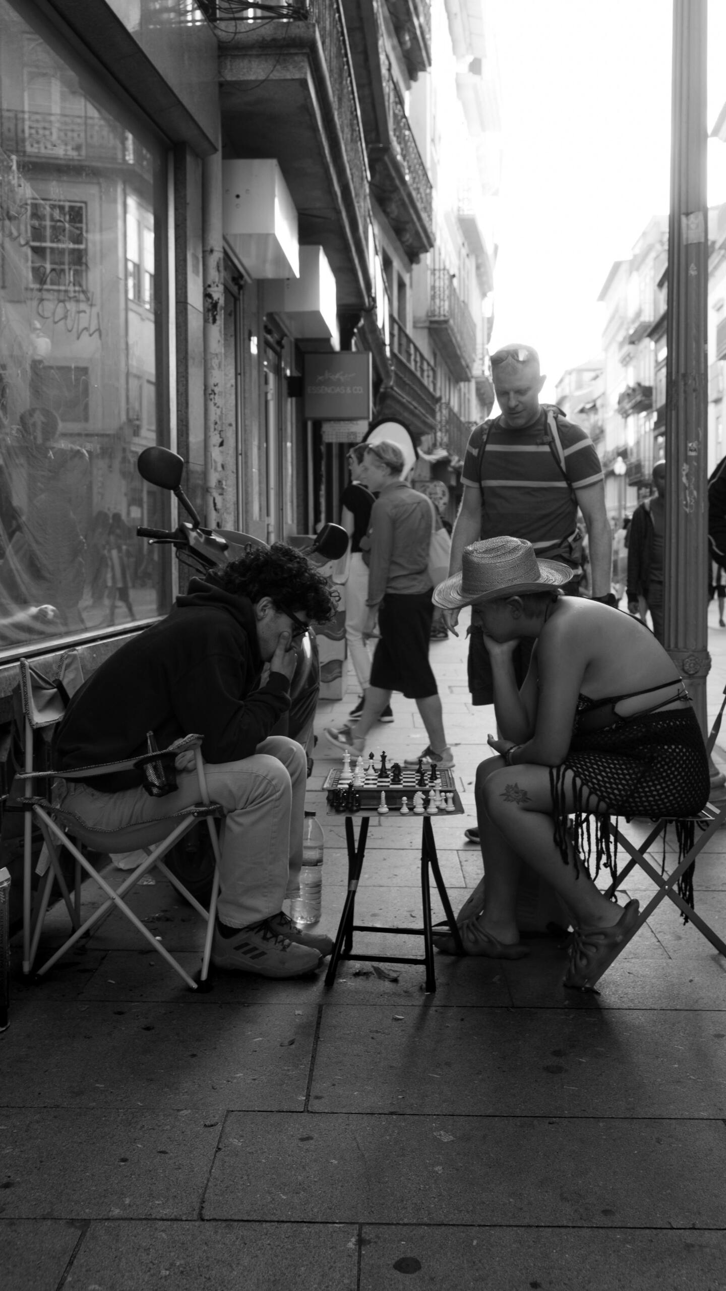 Dos personas jugando al aledrez en la vereda.