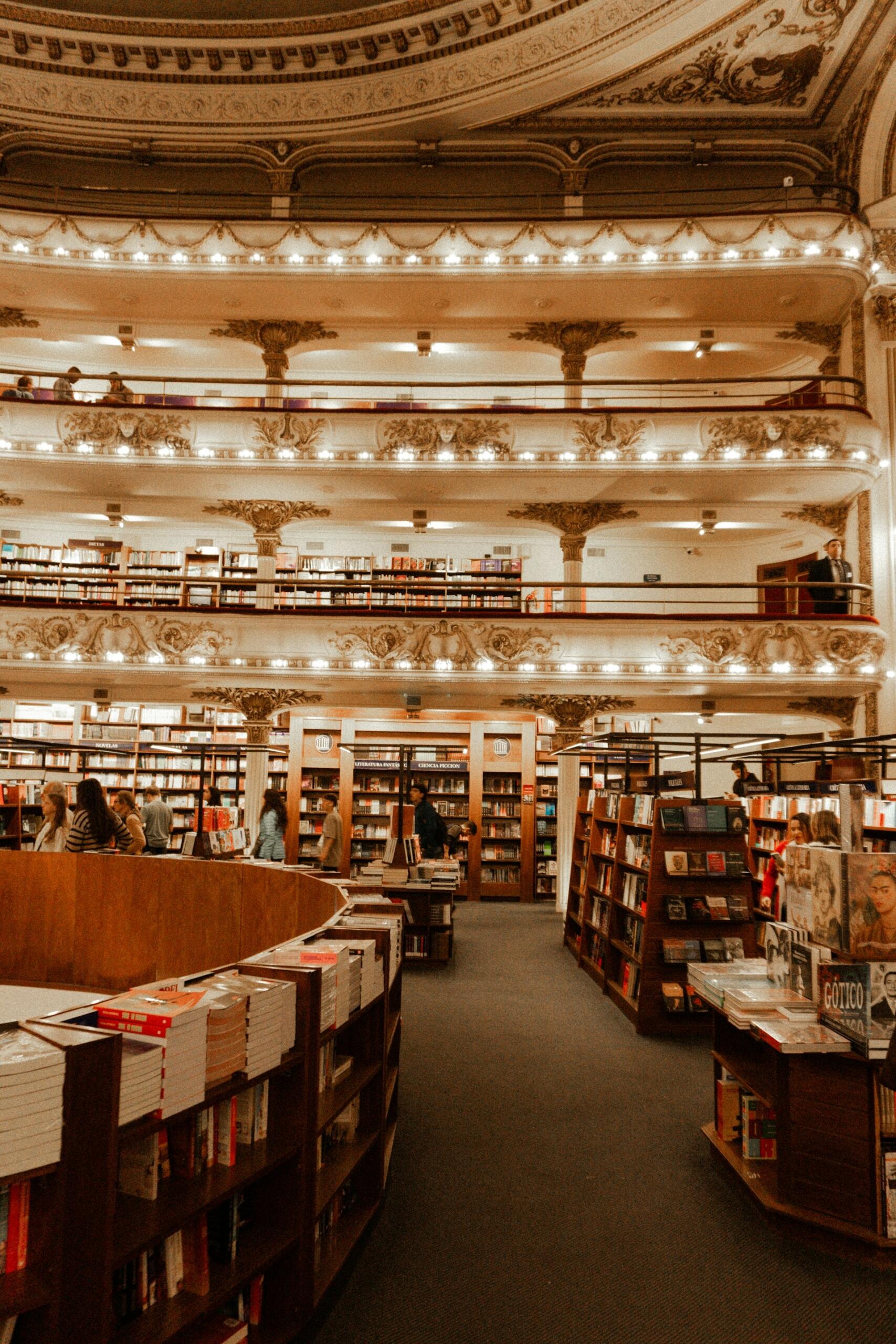 Interior de biblioteca histórica con múltiples pisos, estanterías de libros y luminarias decorativas. Fotógrafo: Andrei Castanha (@andreicastanha)
