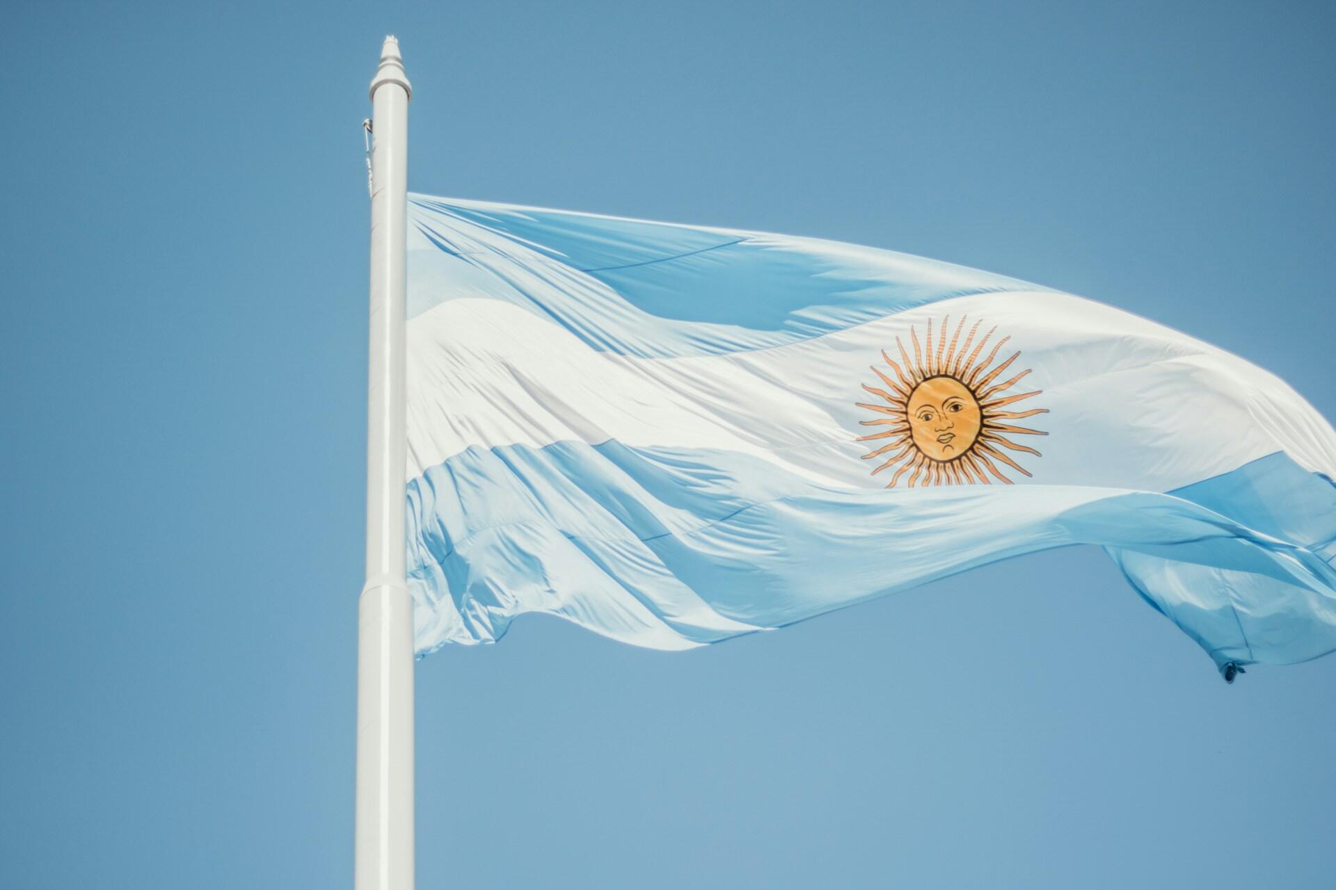 Bandera argentina flameando en lo alto del cielo, que representa el mayor símbolo patrio creado por Manuel Belgrano. Fuente: Unsplash.