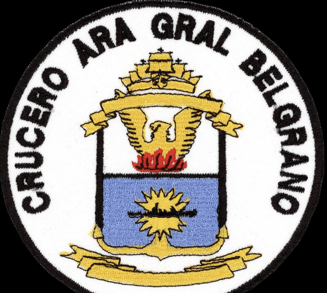 Parche bordado sobre fondo oscuro, que representa el escudo y emblema oficial del histórico Crucero ARA General Belgrano. Fuente: Wikimedia Commons.