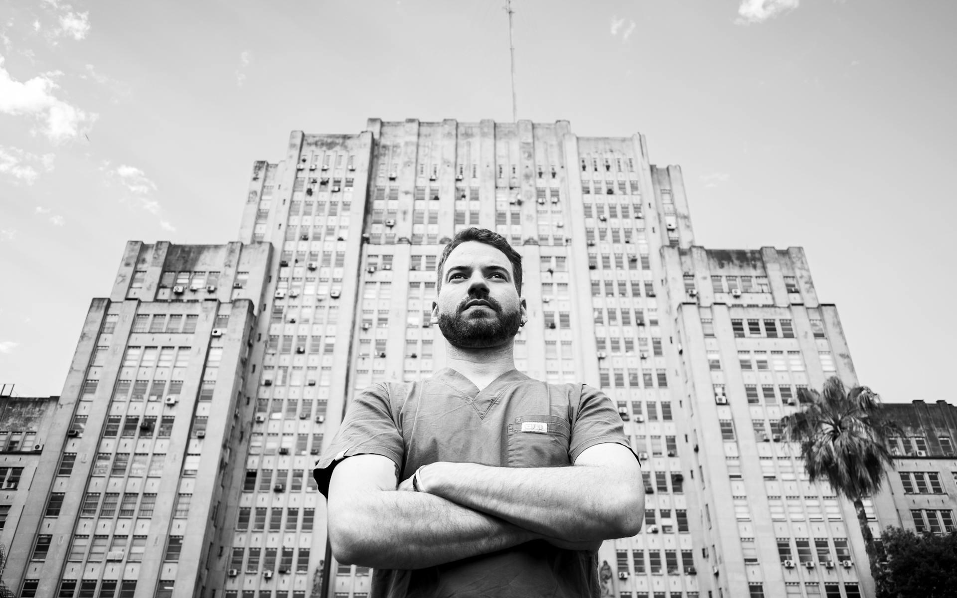 Retrato en blanco y negro de un médico serio de pie frente a un hospital en Buenos Aires.