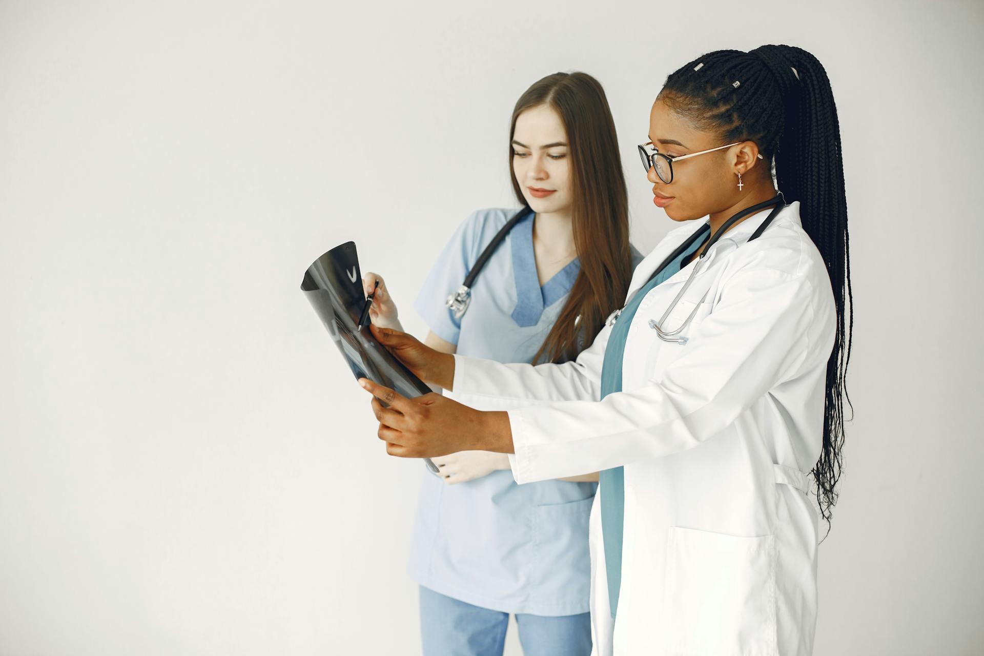 Dos mujeres con delantal blanco mirando una radiografía.