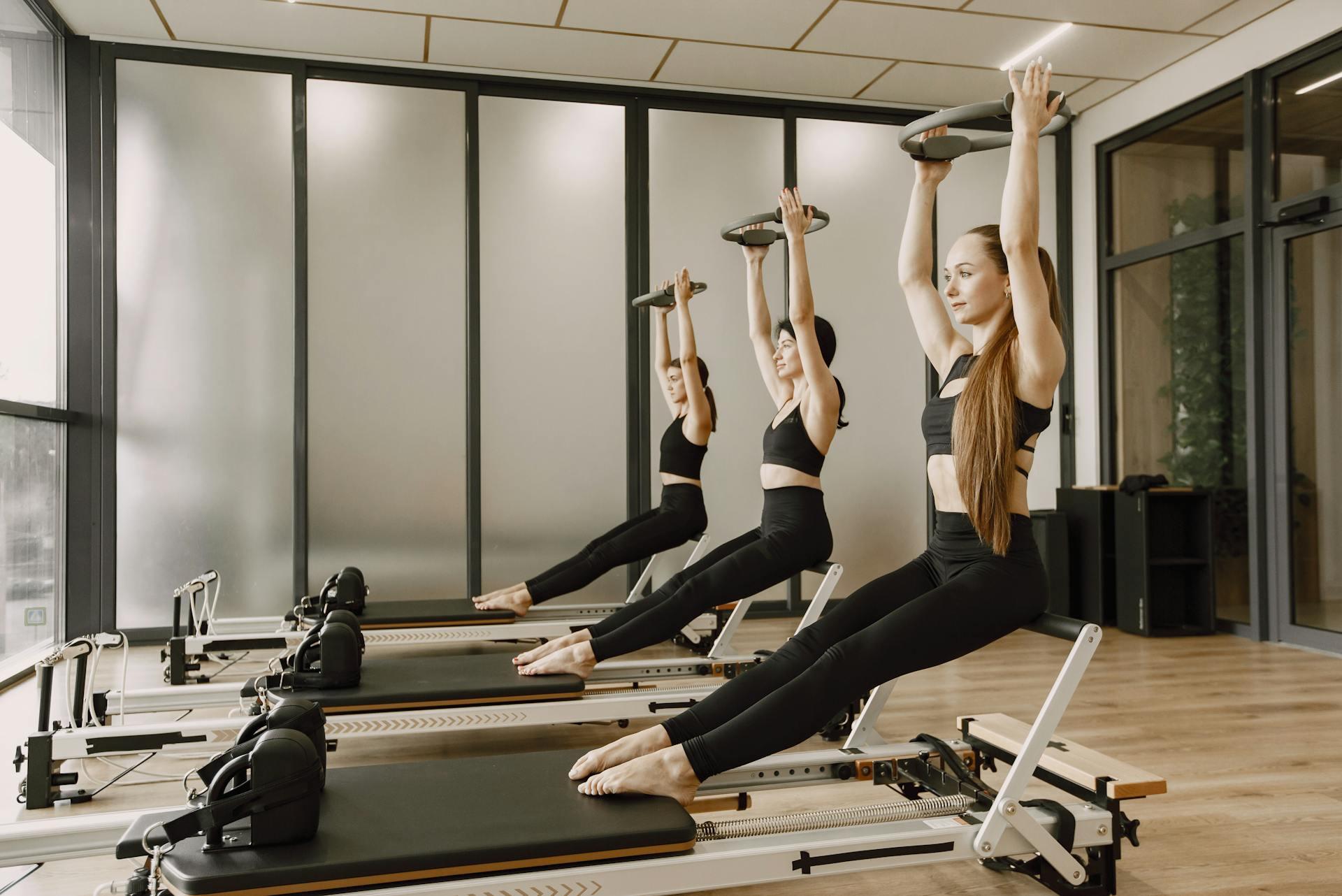 Tres mujeres haciendo ejercicio sobre la camilla de pilates.