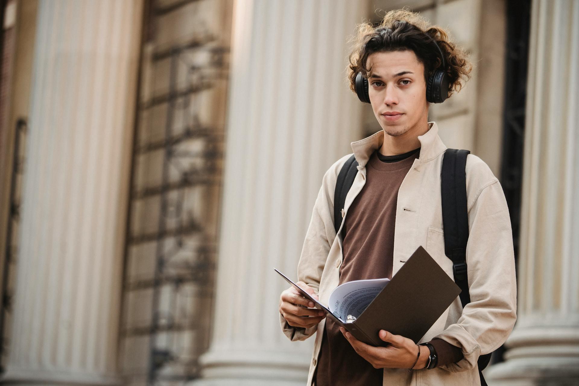 Joven con auriculares sosteniendo una carpeta.