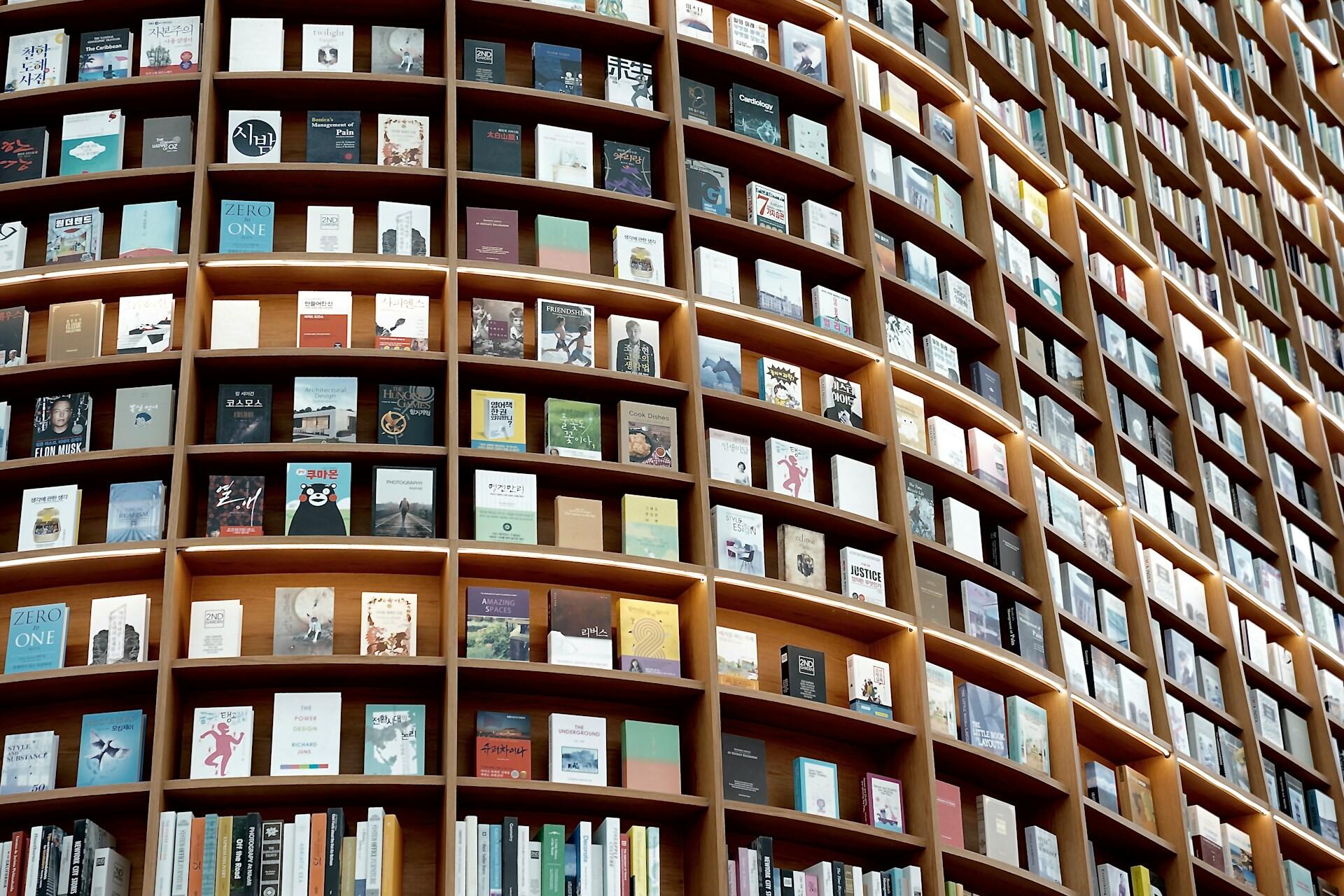 Librería moderna con estanterías de madera llenas de libros diversos. Fotógrafo: Moon Kim (@moonkim)