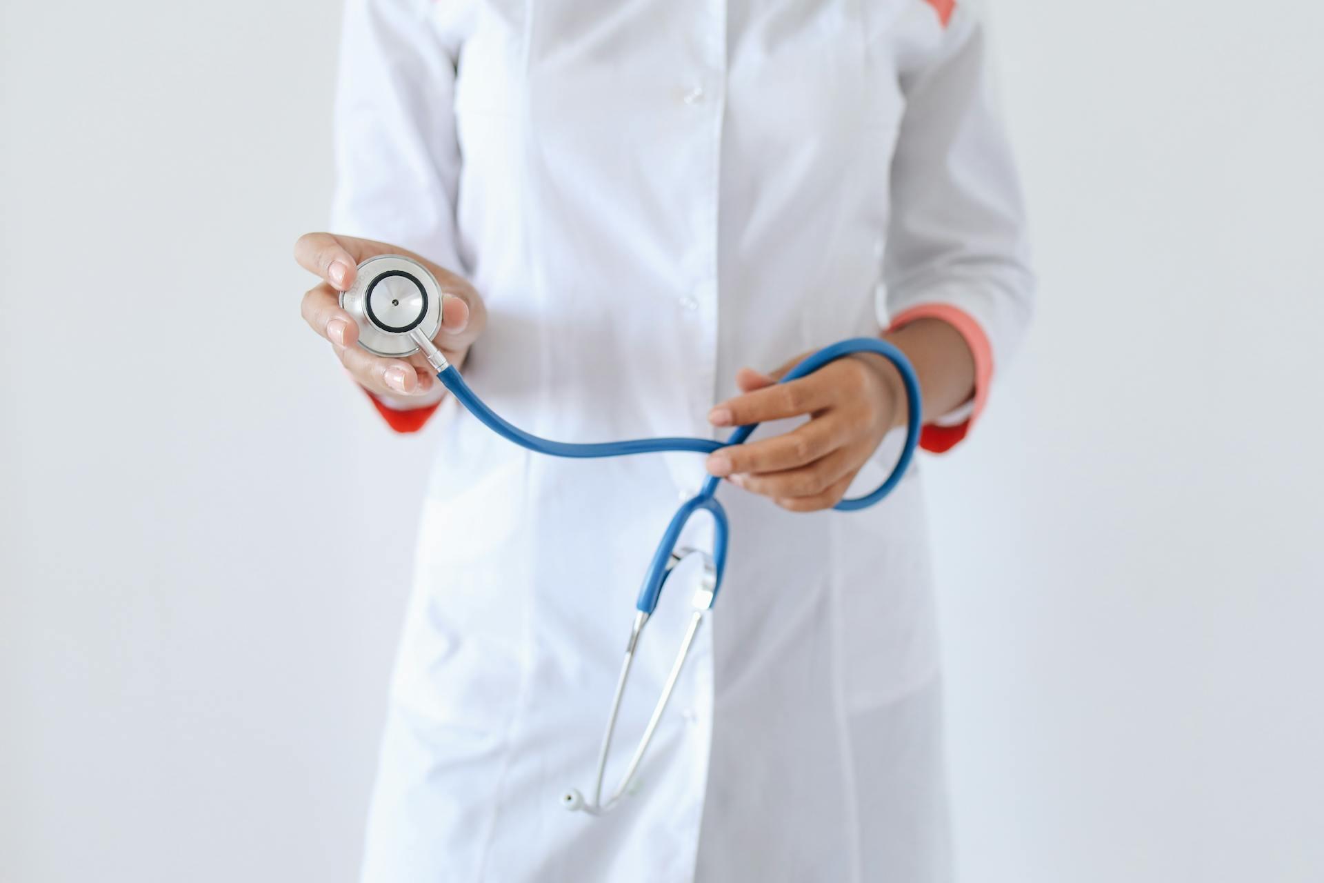Médica con delantal blanco sosteniendo un estetoscopio.