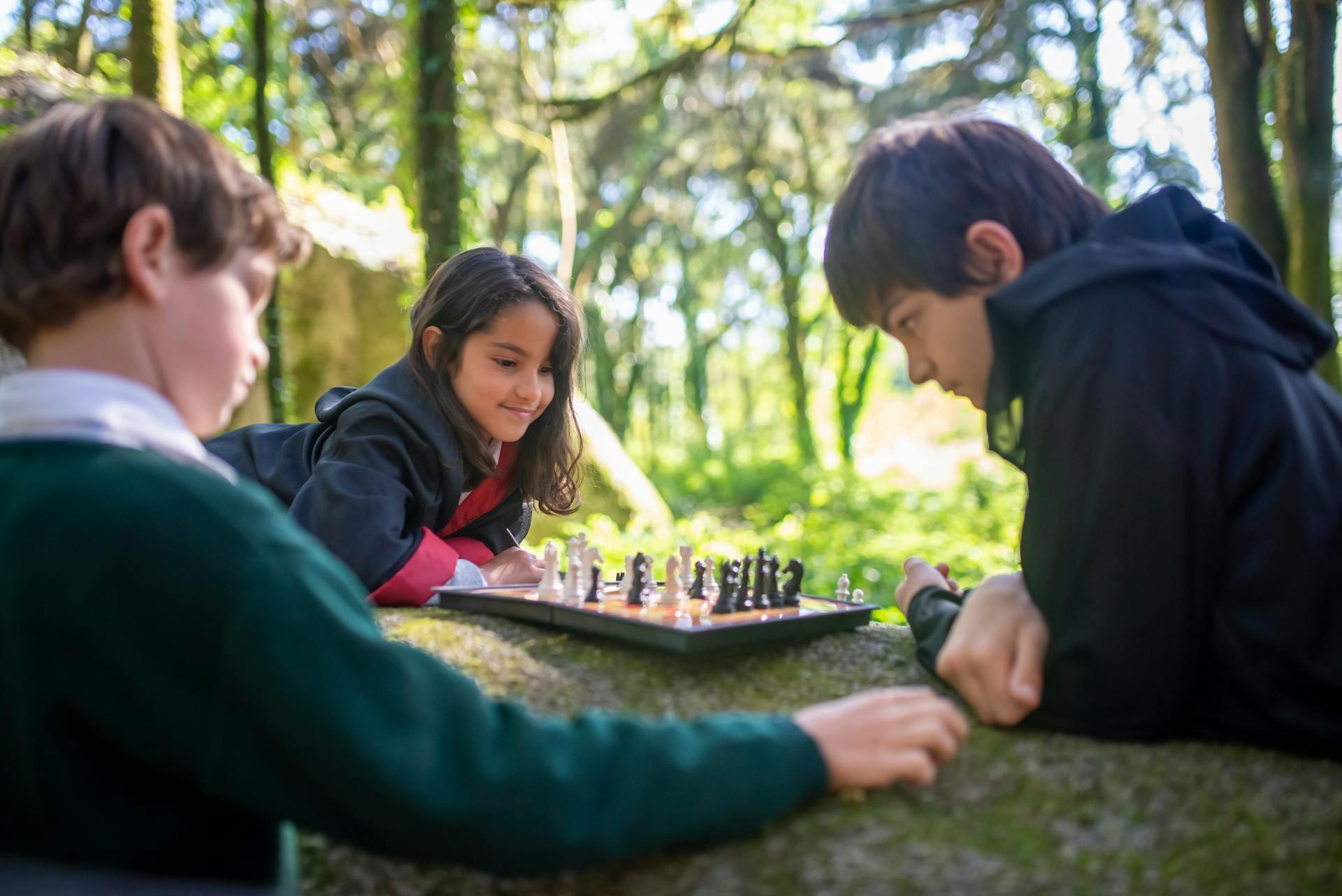 Niños jugando al ajedrez en la naturaleza.
