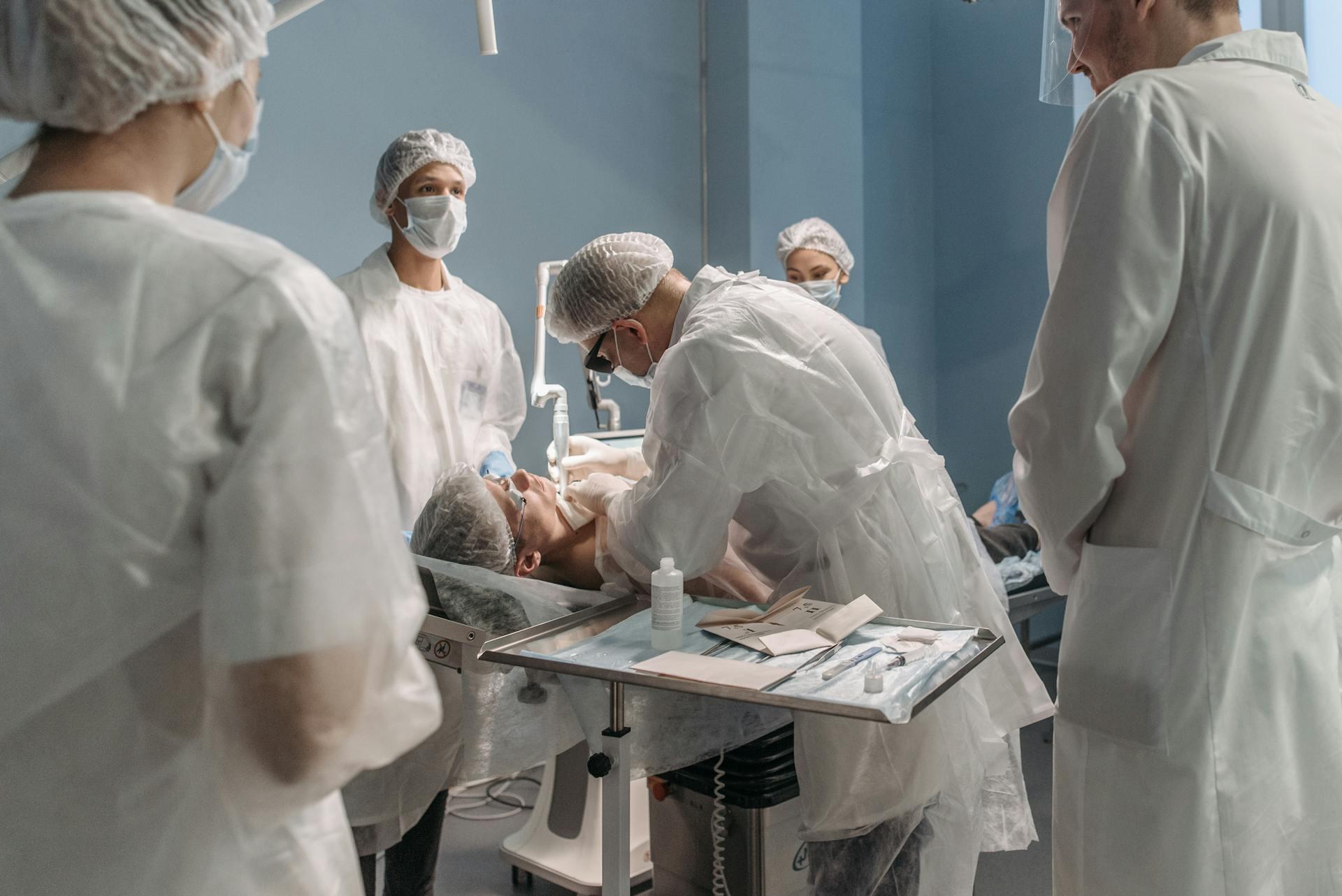 Equipo de médicos vestidos de blanco realizando procedimiento quirúrjuco en quirófano.