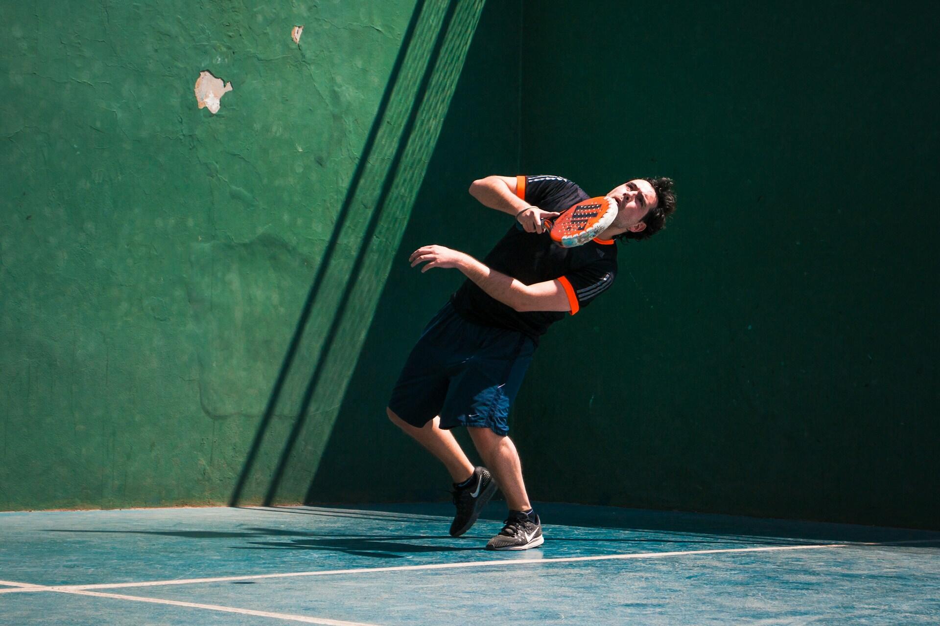 Jugador de pádel realizando un remate técnico en una cancha con paredes verdes en Buenos Aires. Fotografía de Luis Llerena.