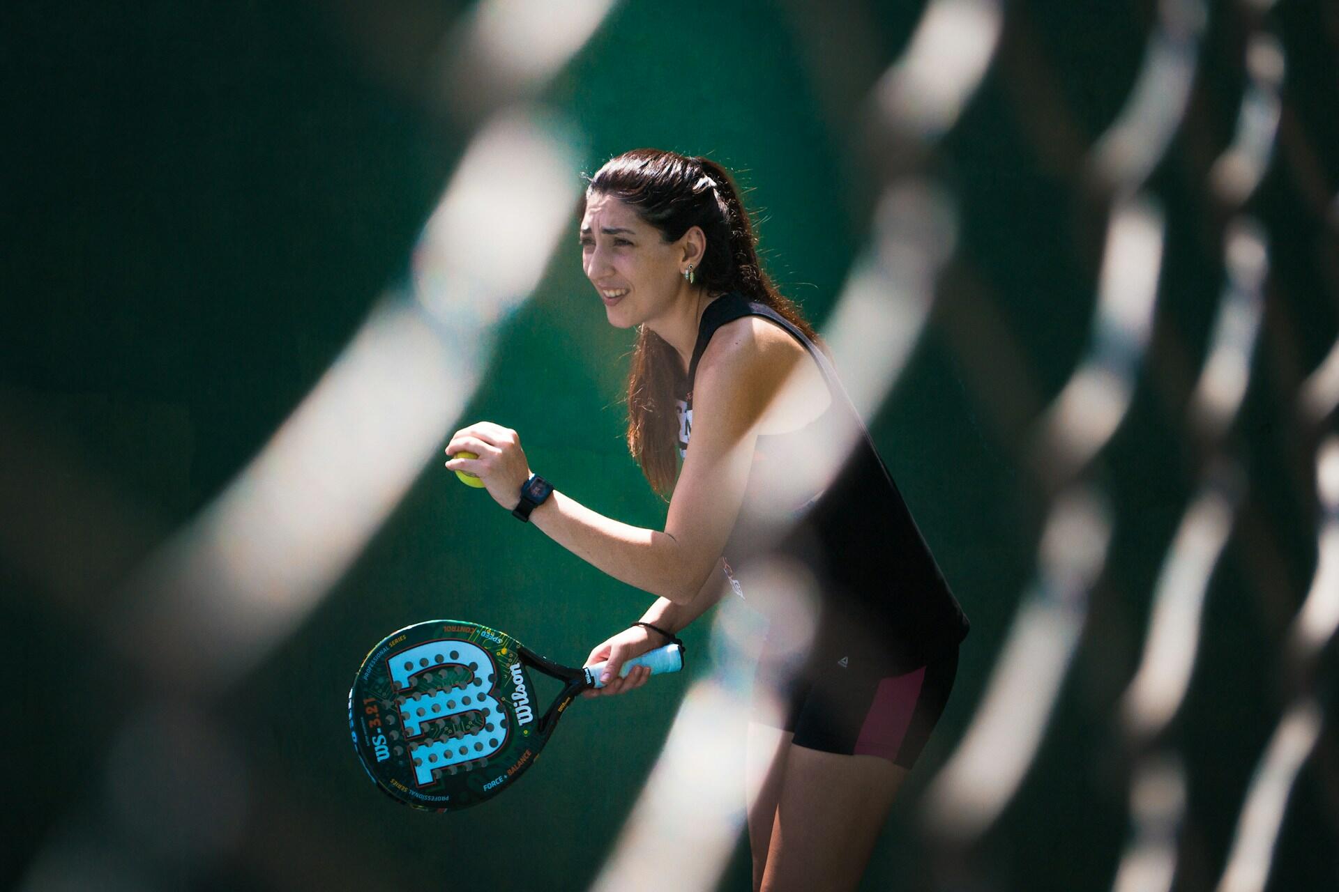 Mujer joven preparándose para realizar un saque durante un partido de pádel, sosteniendo una pala Wilson. Fuente: Unsplash