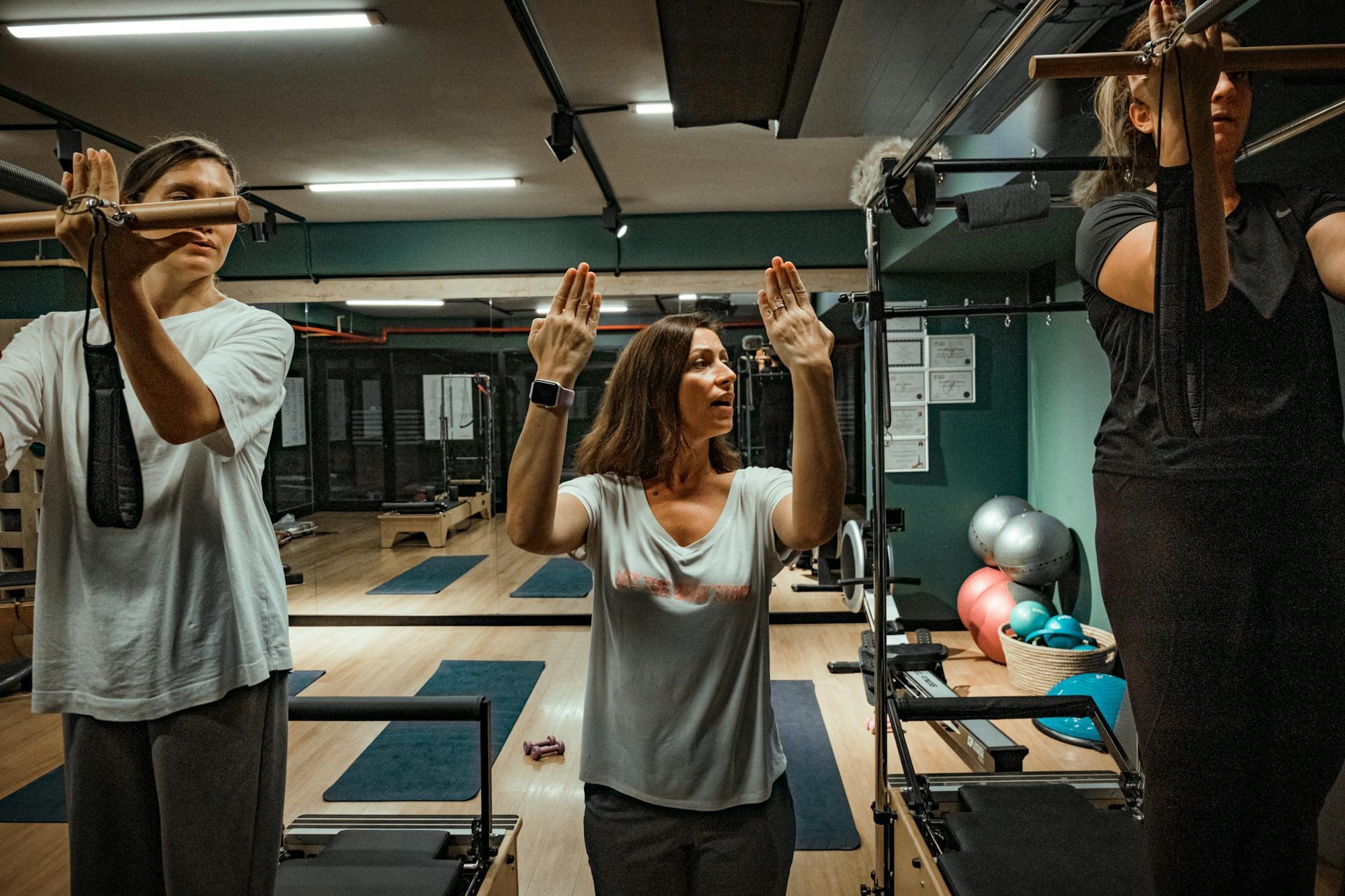 Profesora y alumnos en la clase de pilates con camillas.
