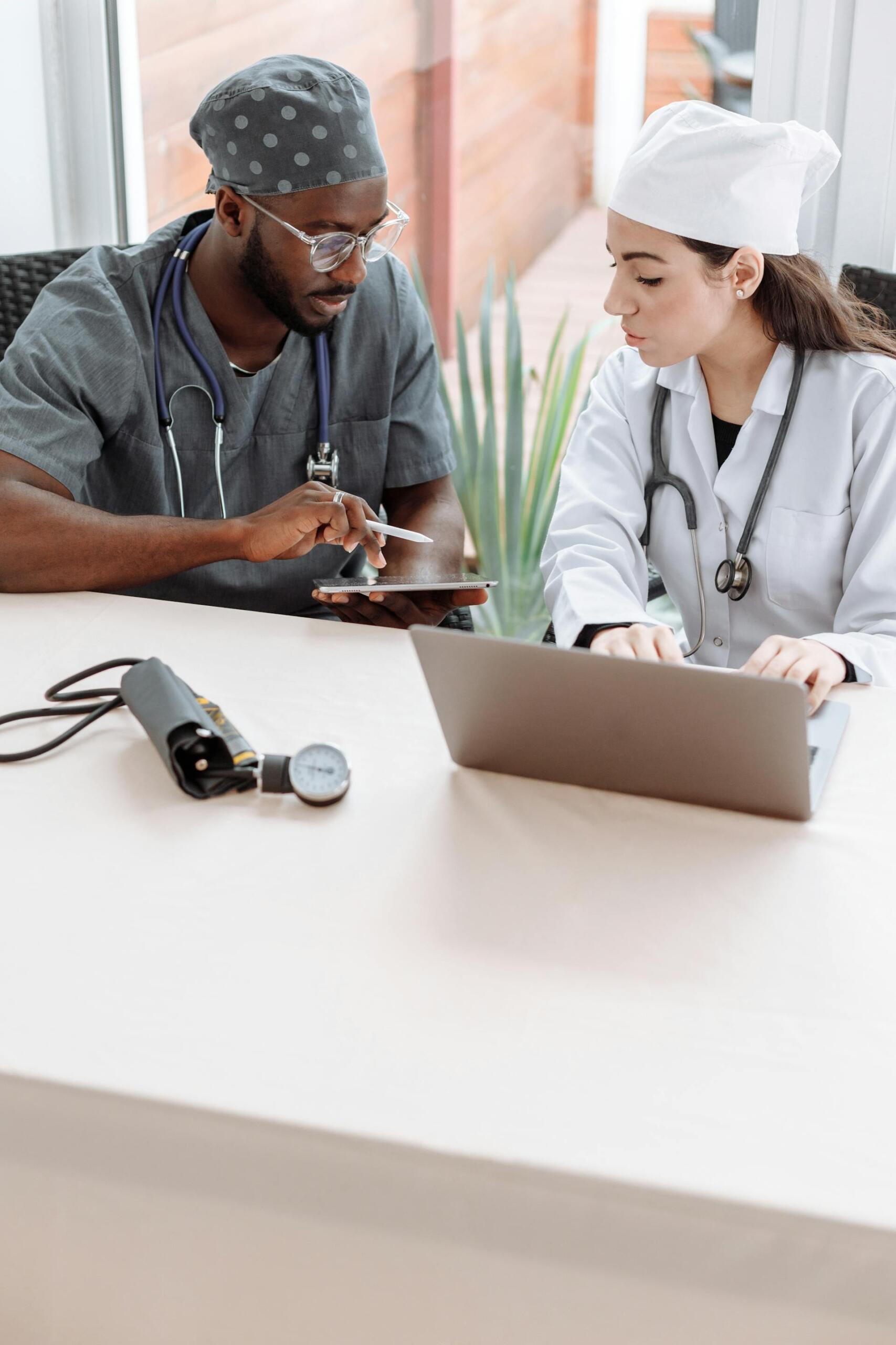 Médico y médica sentados frente a la pc.
