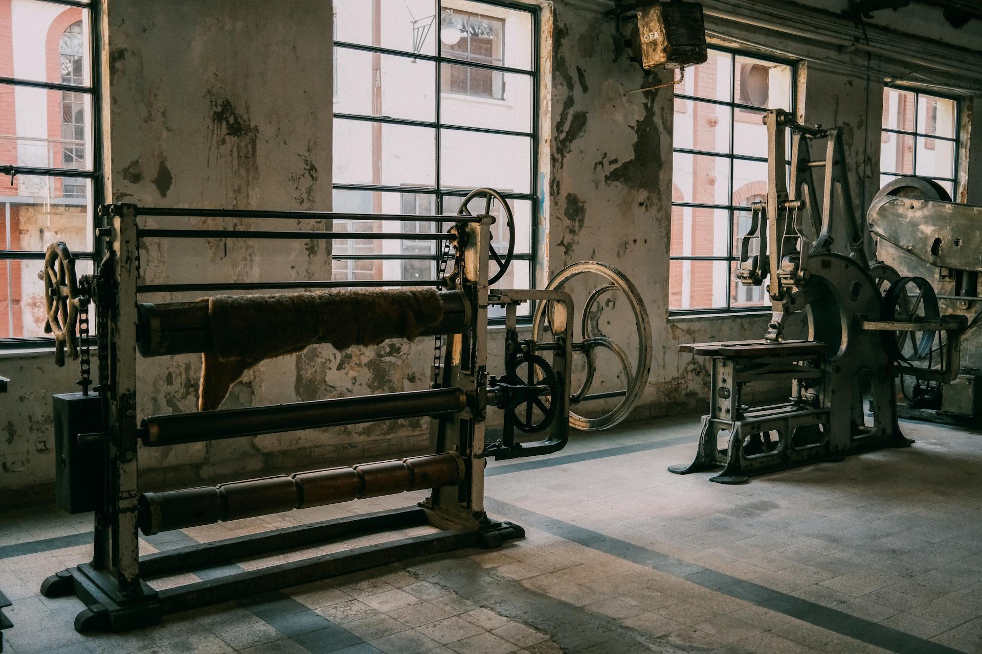 Maquinaria industrial antigua en una fábrica rústica y abandonada con paredes texturizadas.