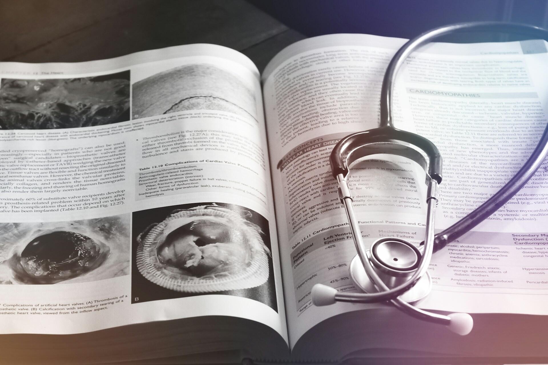Mesa de estudio, libro abierto de patología cardíaca junto a un estetoscopio profesional. Fuente: Unsplash.