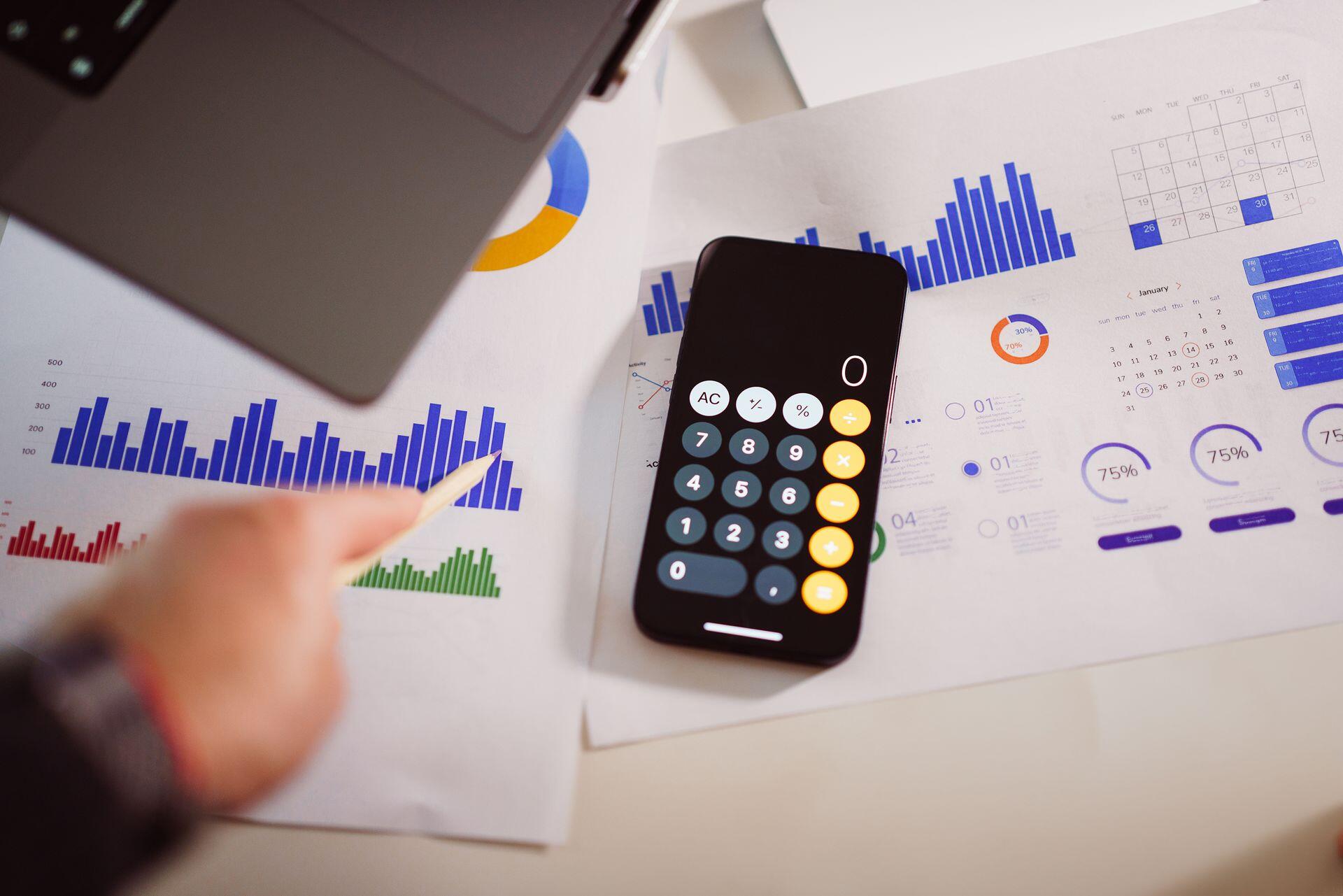 Calculadora de Iphone apoyada sobre papeles con gráficos contables.