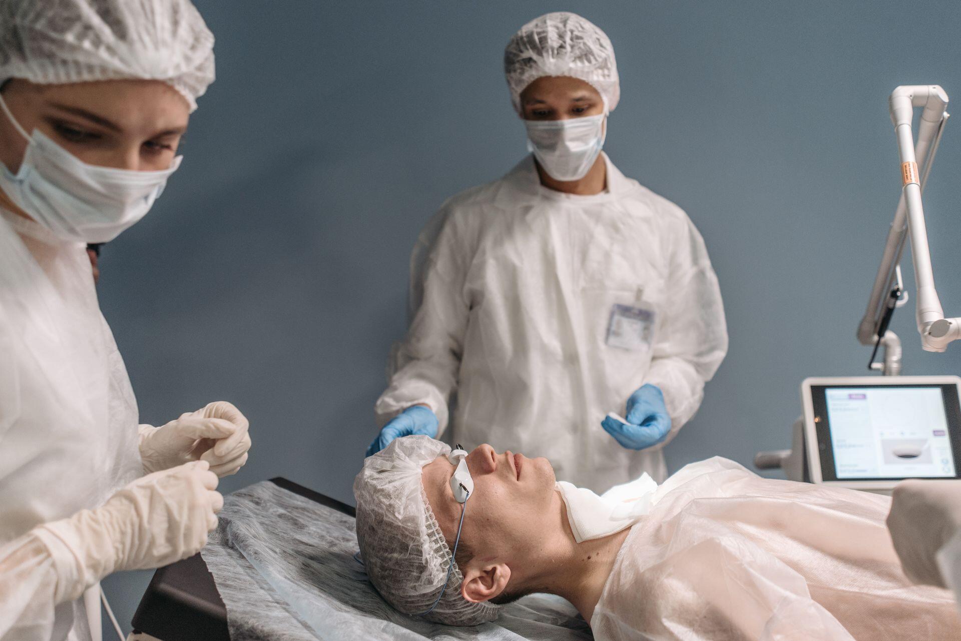 Sala de procedimientos clínicos, médicos con equipo de protección atendiendo a un paciente, Pavel Danilyuk.