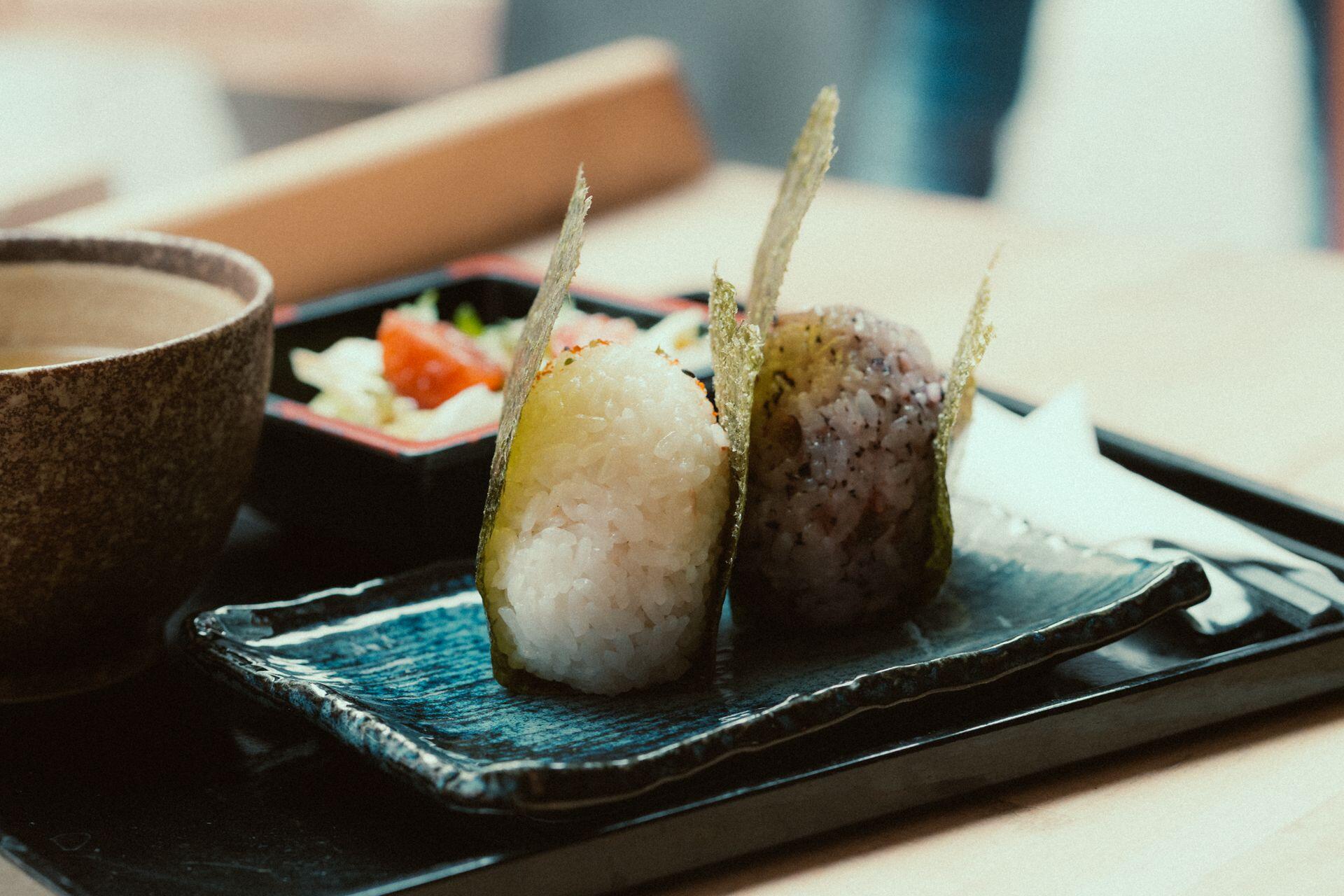 Bolitas de arroz recubiertas en alga sobre el plato azul.