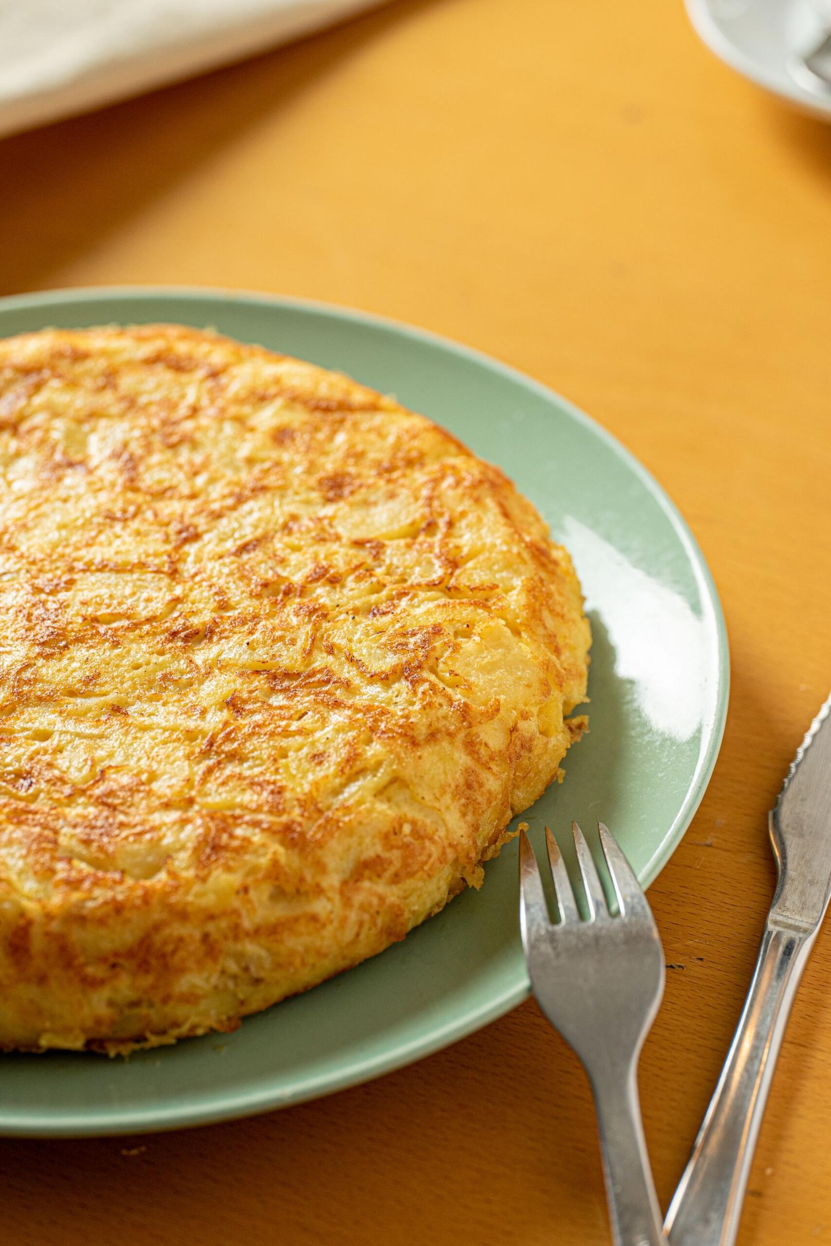 Tortilla de papas sevida en un plato verde.